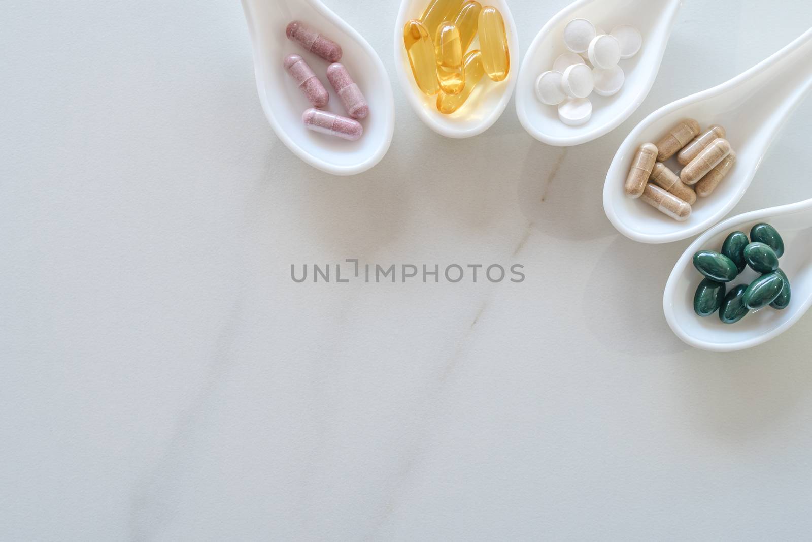 Top view of natural vitamin supplement on white spoon as frame of marble texture background. Healthy eating lifestyle trend concept. by Suwant