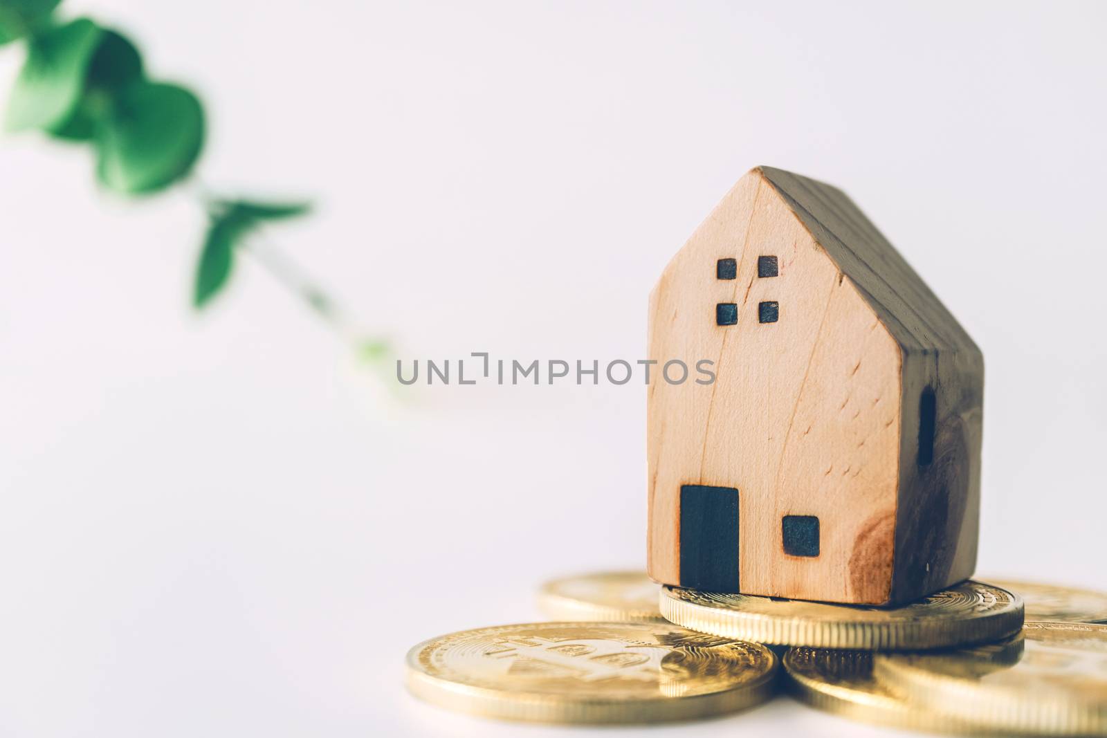 Mini house model on gold coin with clean white copyspace background. Business invest property saving concept.