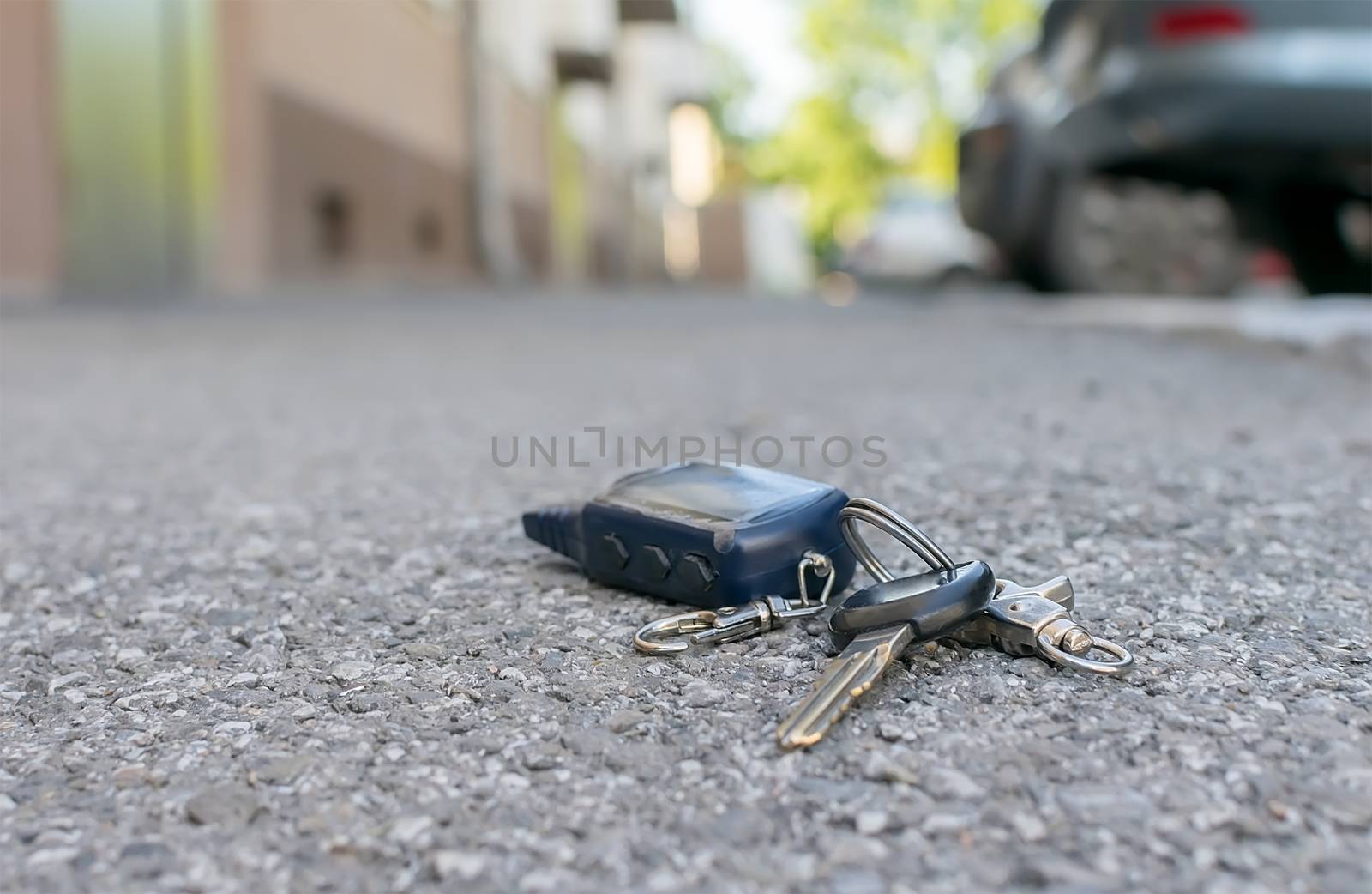 The lost keychain, car alarm remote, lies on the asphalted sidewalk by jk3030