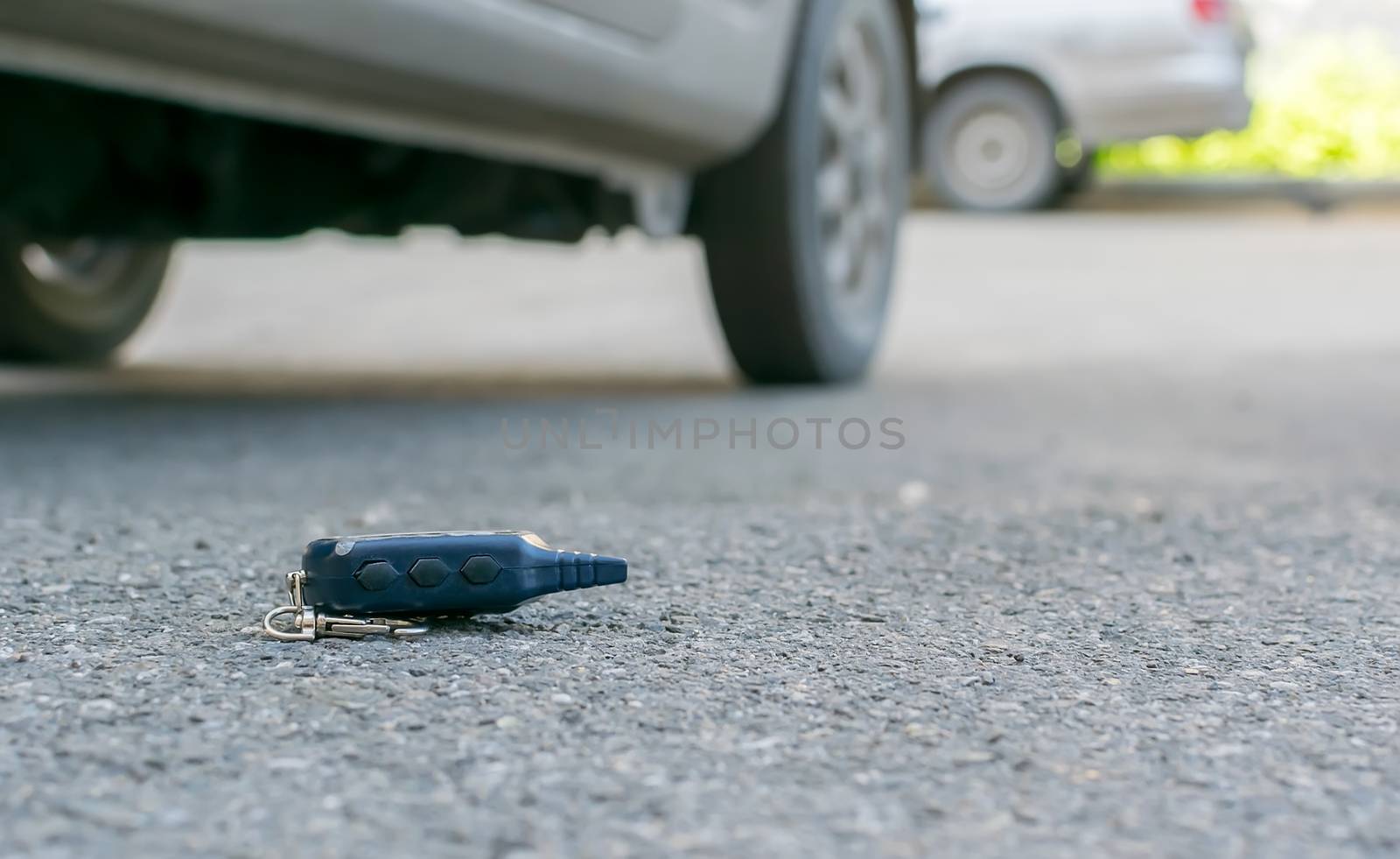 The lost keychain, car alarm remote, lies on the asphalted sidewalk of the road by jk3030