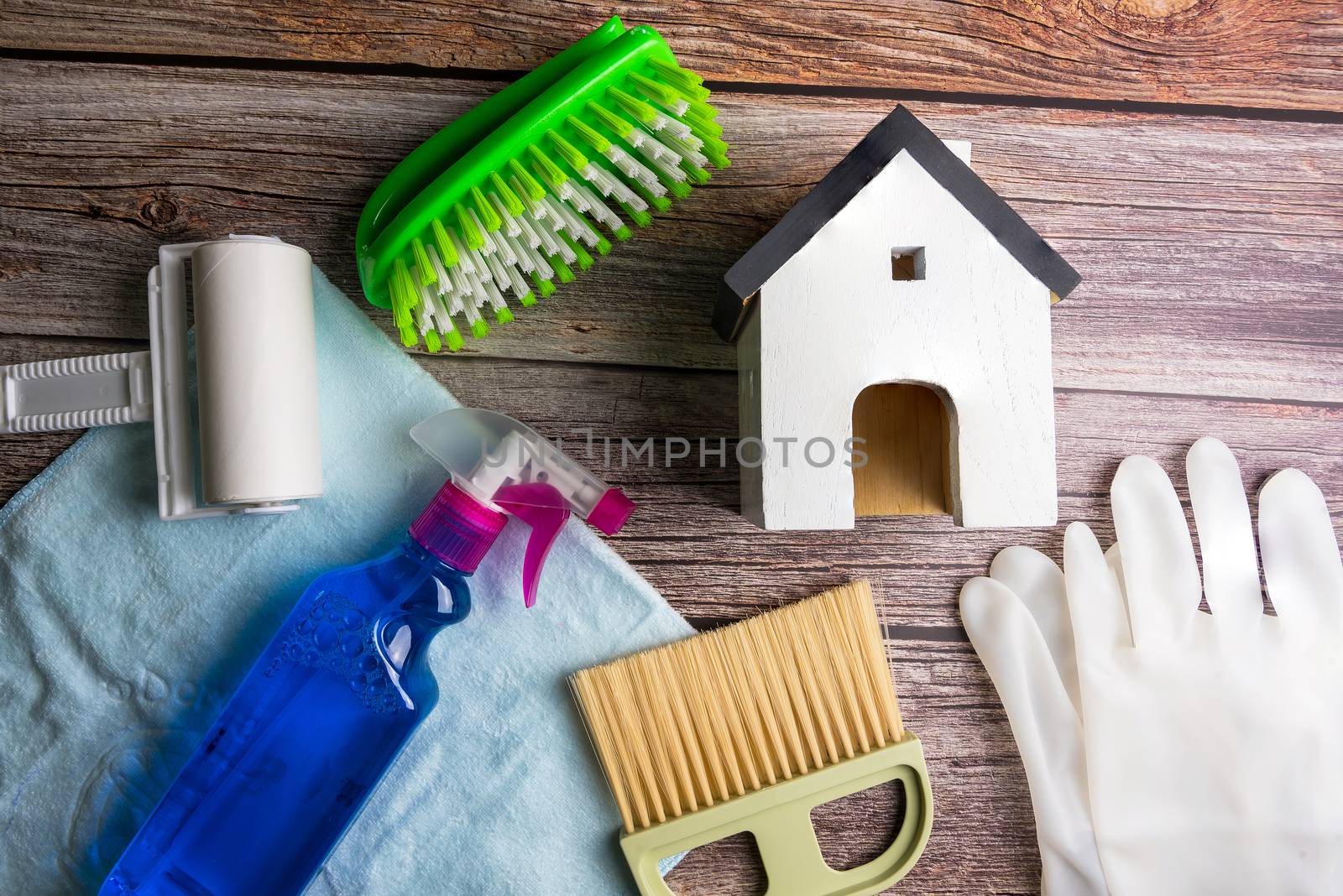 Wooden model white houses and house cleaning equipment on a teble wooden  background. Concept Clean house Keep house clean.
