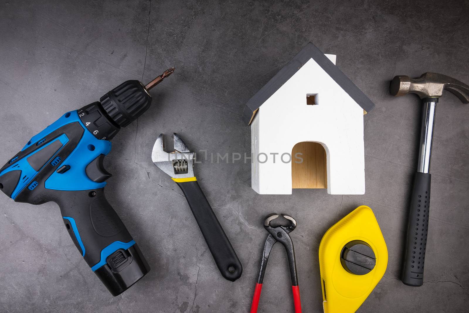 Wooden model white houses and Home Repair Hand Tools on a cement gray background. Concept home repair, Home improvement, Renovate home.