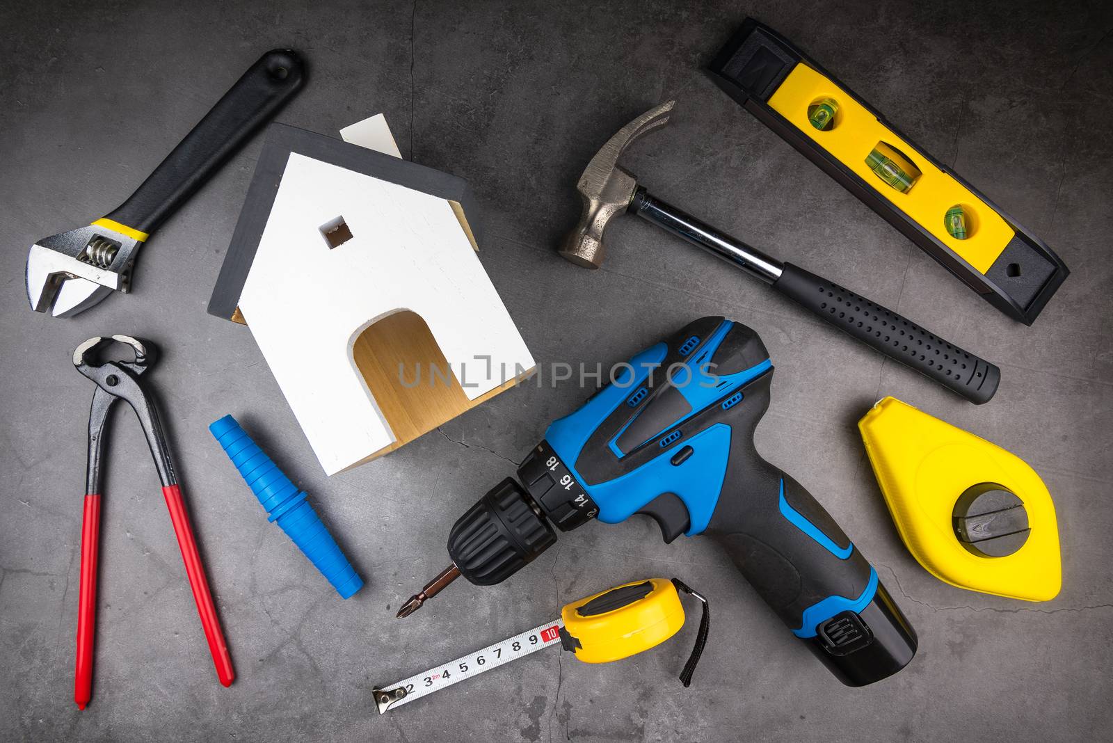 Wooden model white houses and Home Repair Hand Tools on a cement by Bubbers