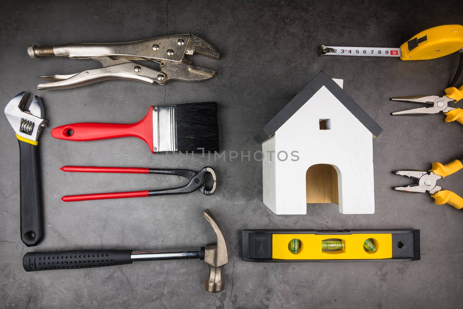 Wooden model white houses and Home Repair Hand Tools on a cement gray background. Concept home repair, Home improvement, Renovate home.
