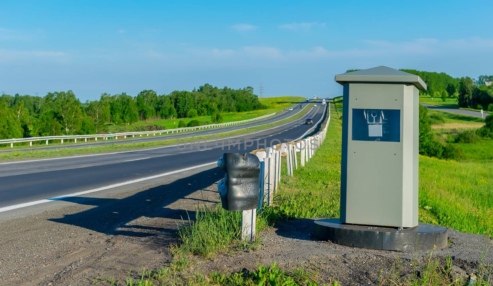 view camera fixing the movement of cars from speeding, which stands on a country road in the summer on the background of passing cars