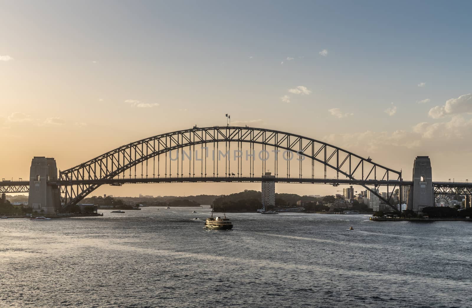 Sydney, Australia - February 12, 2019: Harbour bridge under an evening twilight sky. Ferry boat.