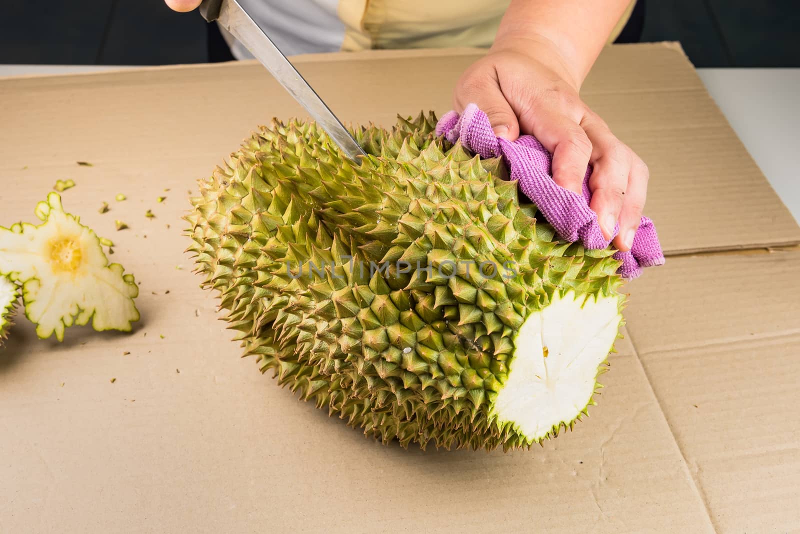 Woman cutting a Durian fruit on the wooden table by using a knif by Bubbers