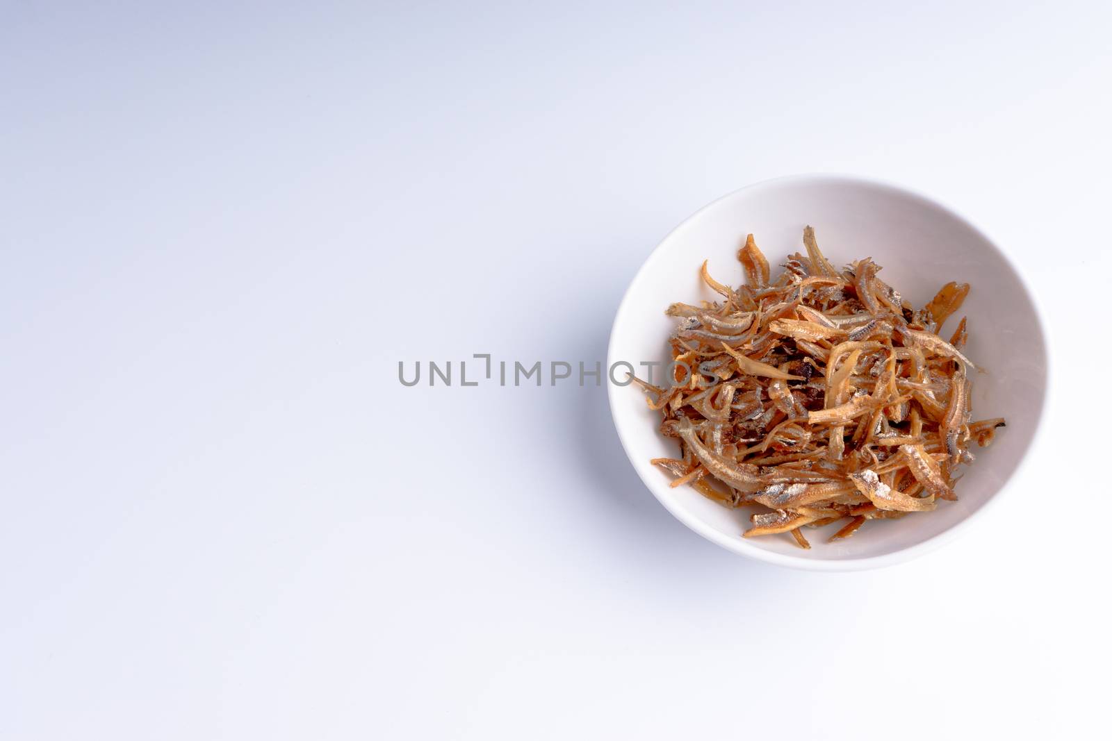 Fried anchovies in bowl close up with selective focus and crop fragment