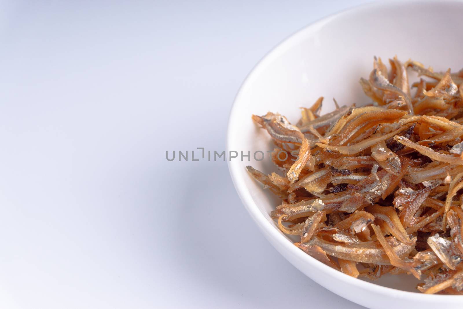 Fried anchovies in bowl close up with selective focus and crop fragment