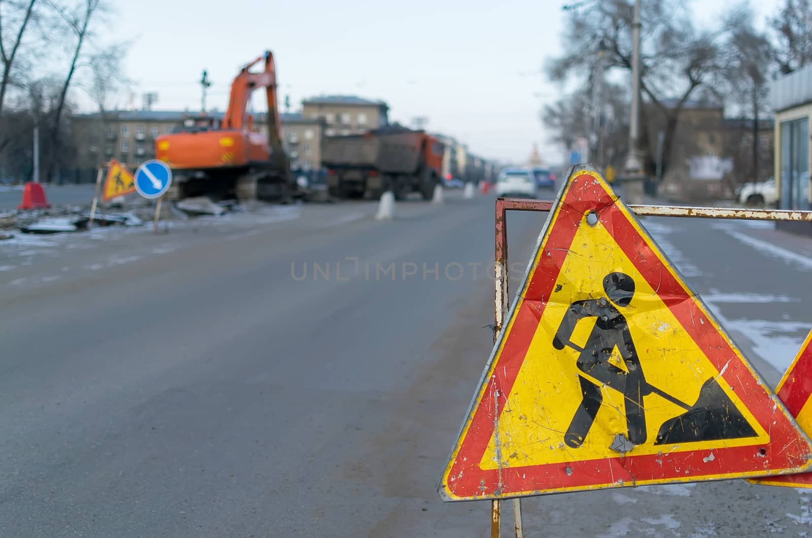 Traffic signs, detour, road repair on the background of the street and the excavator who digs the pit