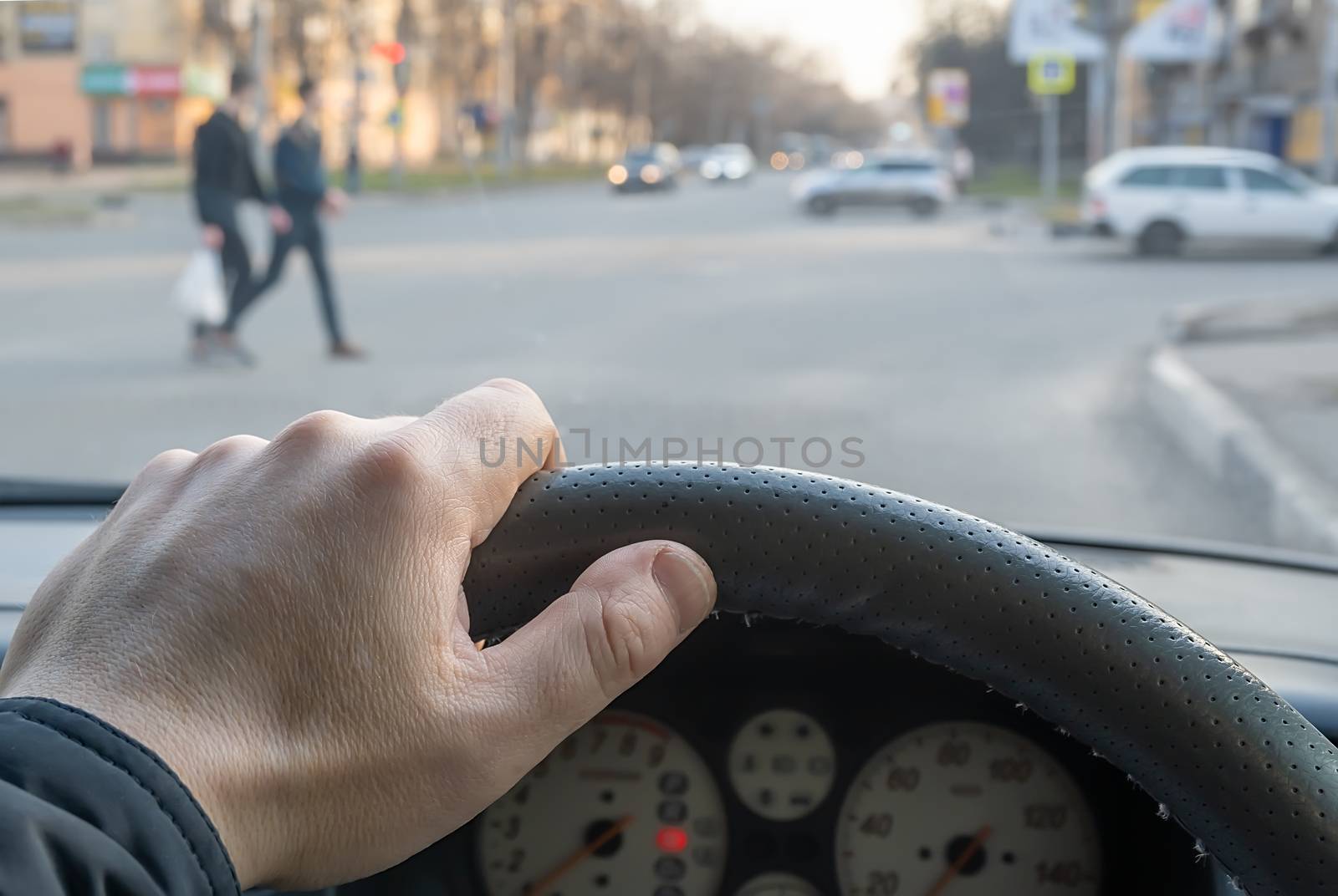 view from the car, the man's hand on the steering wheel of the car, located opposite the pedestrian crossing and pedestrians crossing the road by jk3030