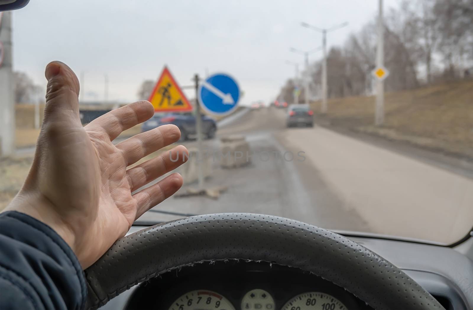 hand, the palm of a driver behind the wheel of a car who is outraged by road repairs and road signs installed by jk3030