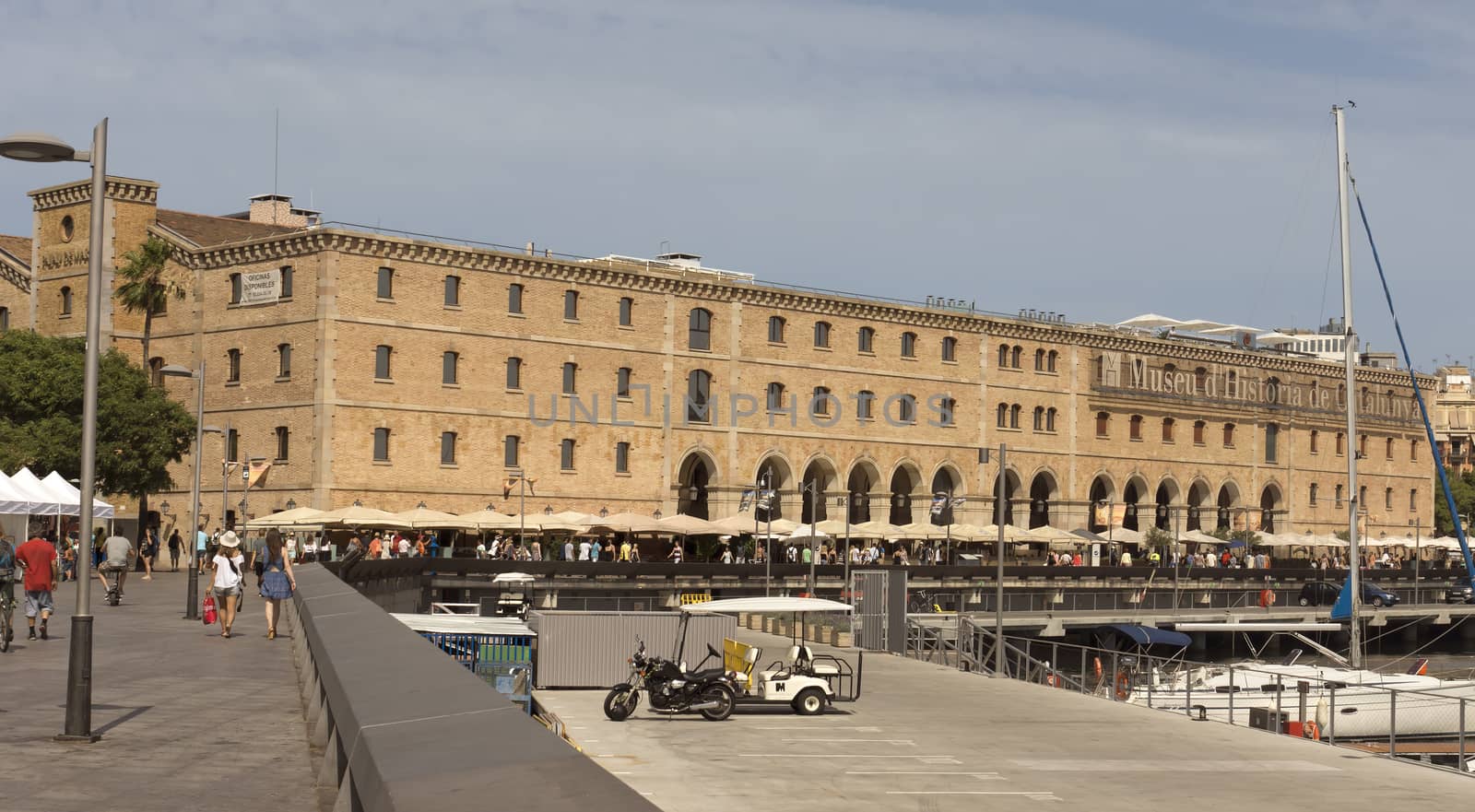 BARCELONA, SPAIN - JULY 4, 2015: The building "Palau de Mar" (1880-1890) home of museum "Museu d'Historia de Catalunya" in front of the harbor.

Barcelona, Spain - July 4, 2015: The building "Palau de Mar" (1880-1890) home of museum "Museu d'Historia de Catalunya" in front of the harbor. People walking at the promenade.