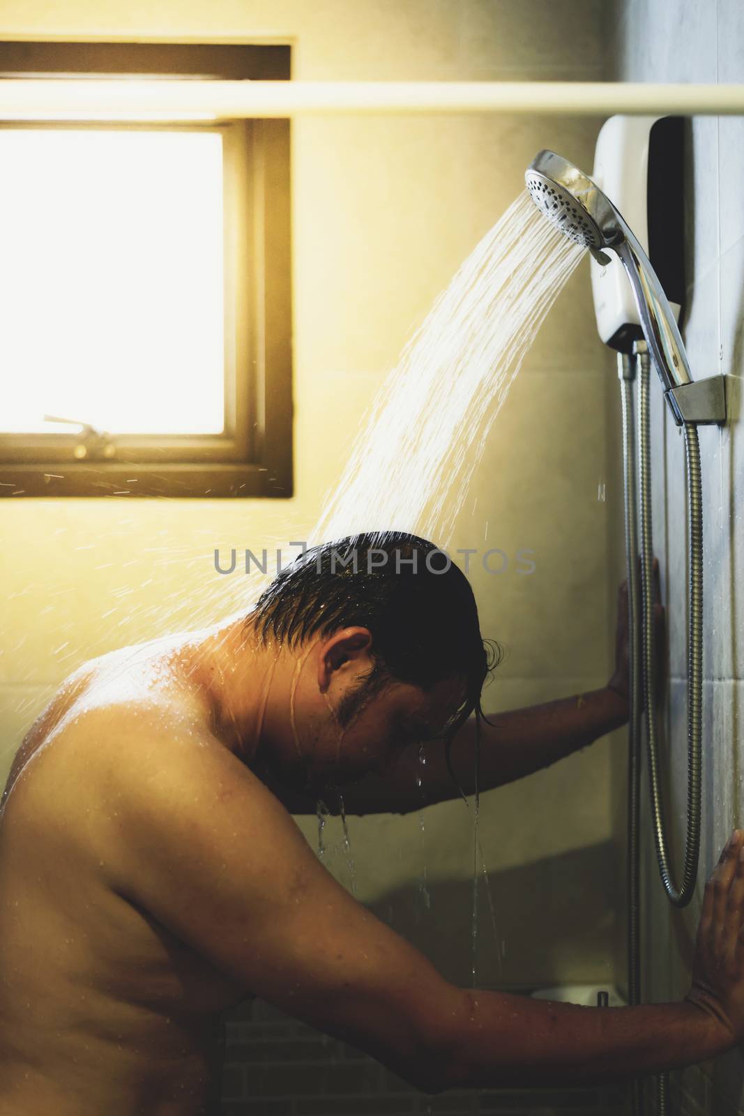Asian man 40s showering in bathroom for clean a body and relax by bare and water drops from shower to the head and all body