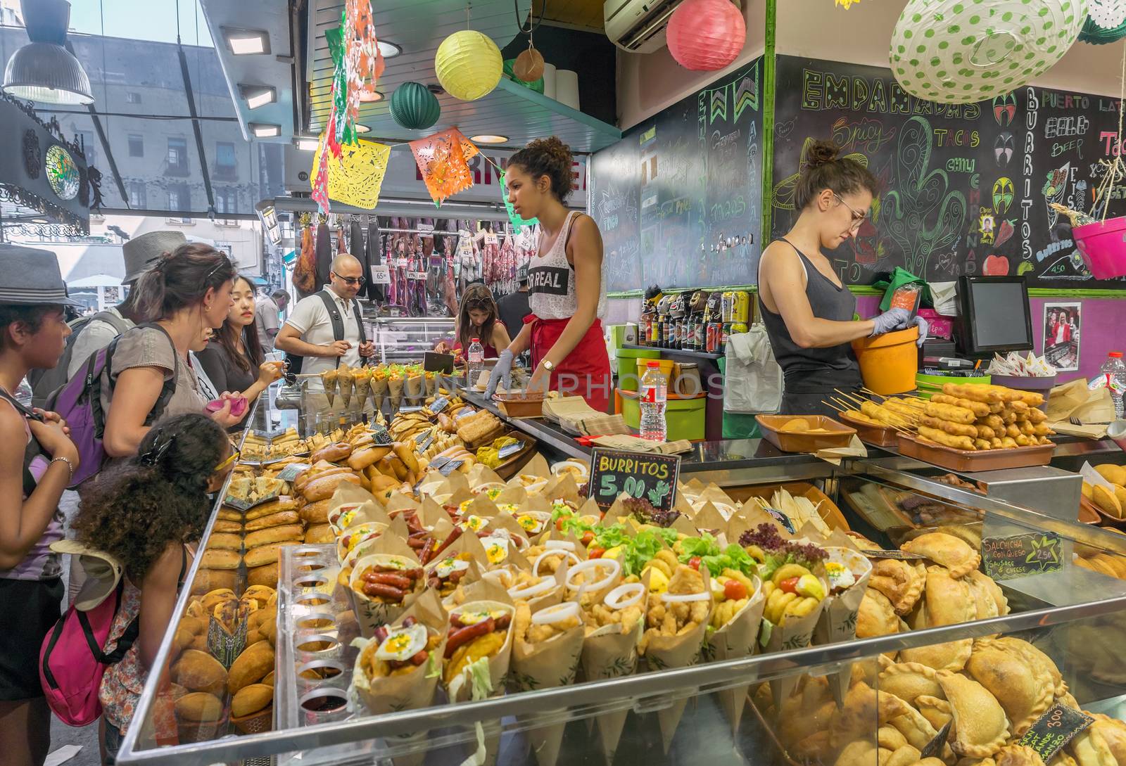 BARCELONA, SPAIN - JULY 6, 2015: Burrito stall at the Boqueria market in Barcelona.

Barcelona, Spain - July 6, 2015: Burrito stall at the Boqueria market in Barcelona. Visitors are choosing snacks and sellers are standing behind the counter.