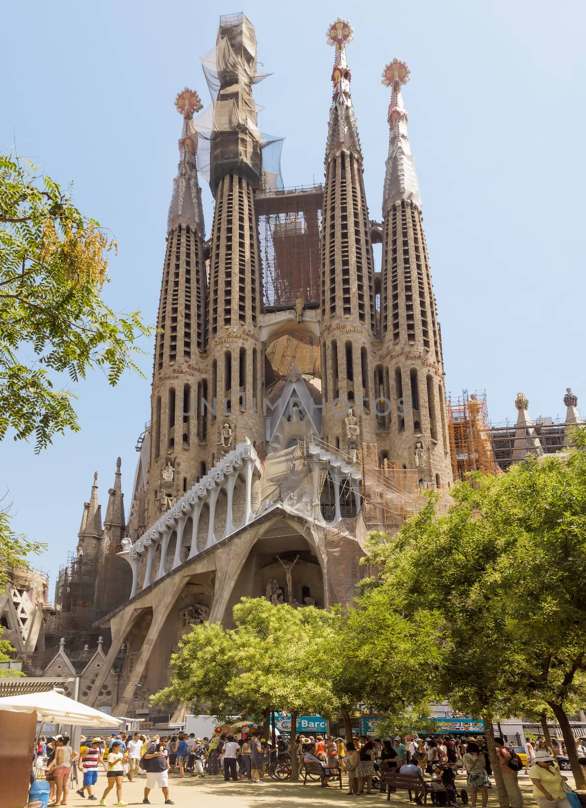 BARCELONA, SPAIN - JULY 6, 2015: La Sagrada Familia - the impressive cathedral designed by Gaudi, which is being build since 19 March 1882 and is not finished yet.

Barcelona, Spain - July 6, 2015: La Sagrada Familia - the impressive cathedral designed by Gaudi, which is being build since 19 March 1882 and is not finished yet. People are walking by street.