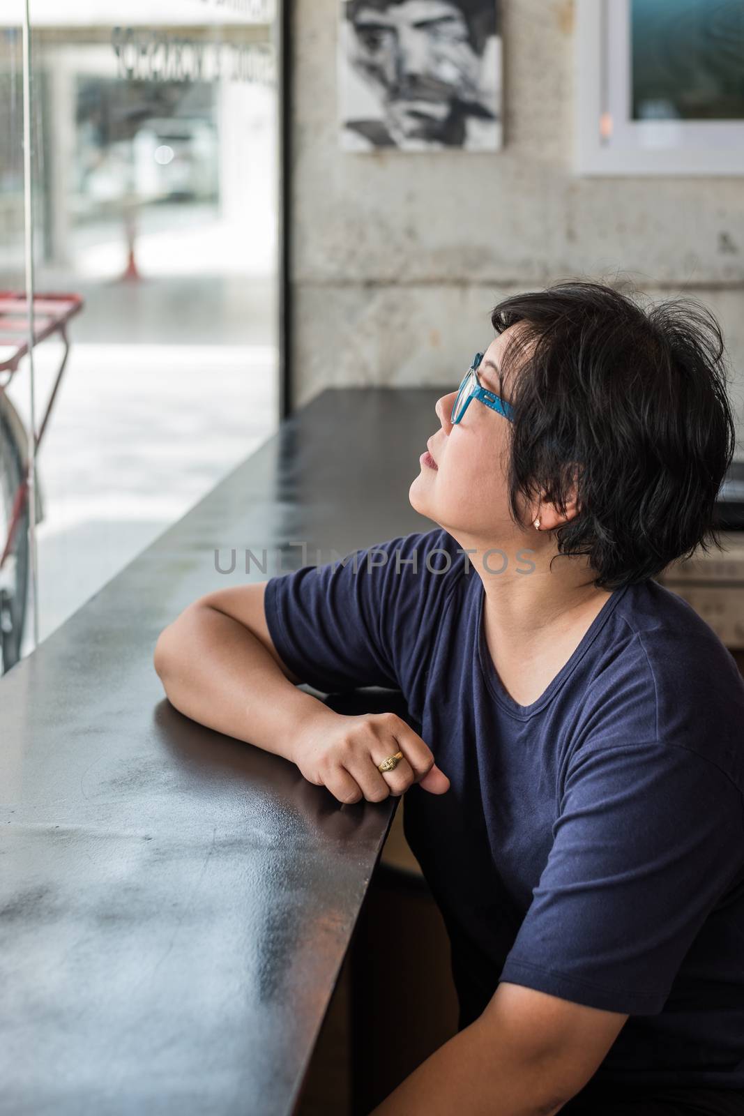 Asian woman 40s white skin with eyeglass sitting and have a doubt and think gesture in a coffee shop cafe for waiting something with a red bicycle vintage style