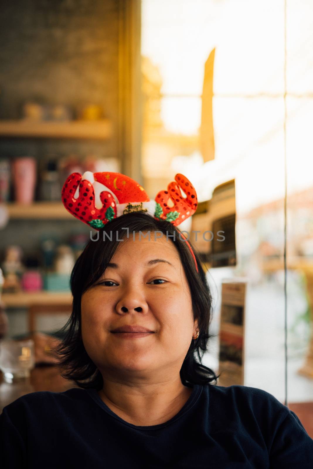 Asian woman 40s white skin have a laughing smile gesture in a coffee shop cafe with santa claus headband in merry christmas and new yaer celebration