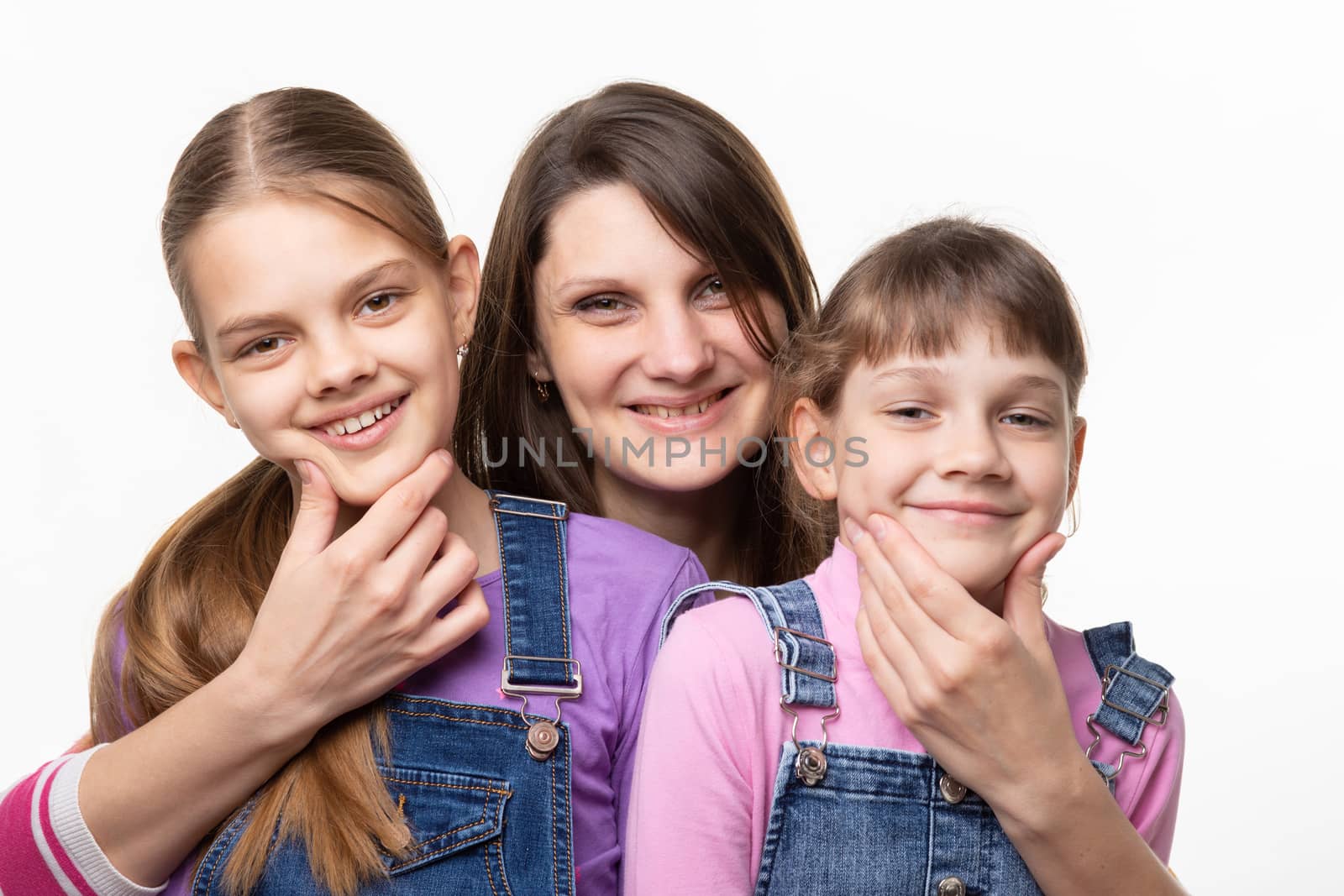 Mom cheerfully holds the children by the chin and looks in the frame