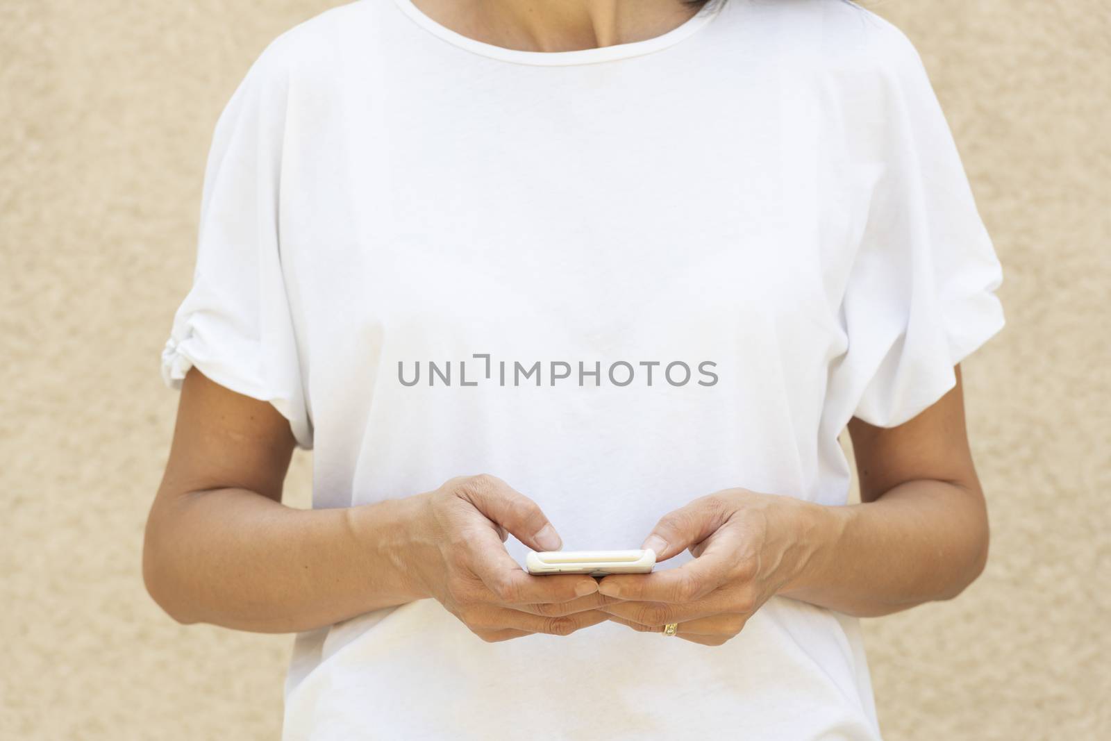 Woman in the forty's using a smartphone with white t-shirt for background or presentation and with large copy space