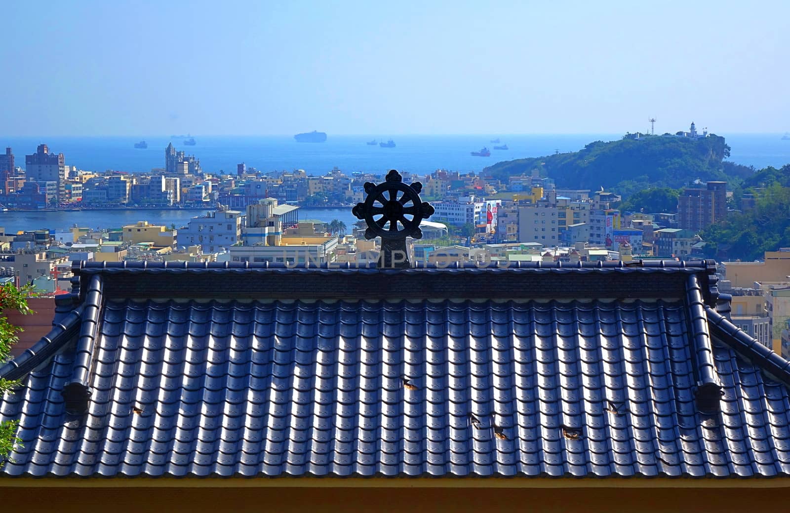 KAOHSIUNG, TAIWAN -- APRIL 29, 2017: View of Kaohsiung Port and Chijin Island over the roof of the Qian Guang Temple. The roof is decorated with a Dharma Wheel of Life.