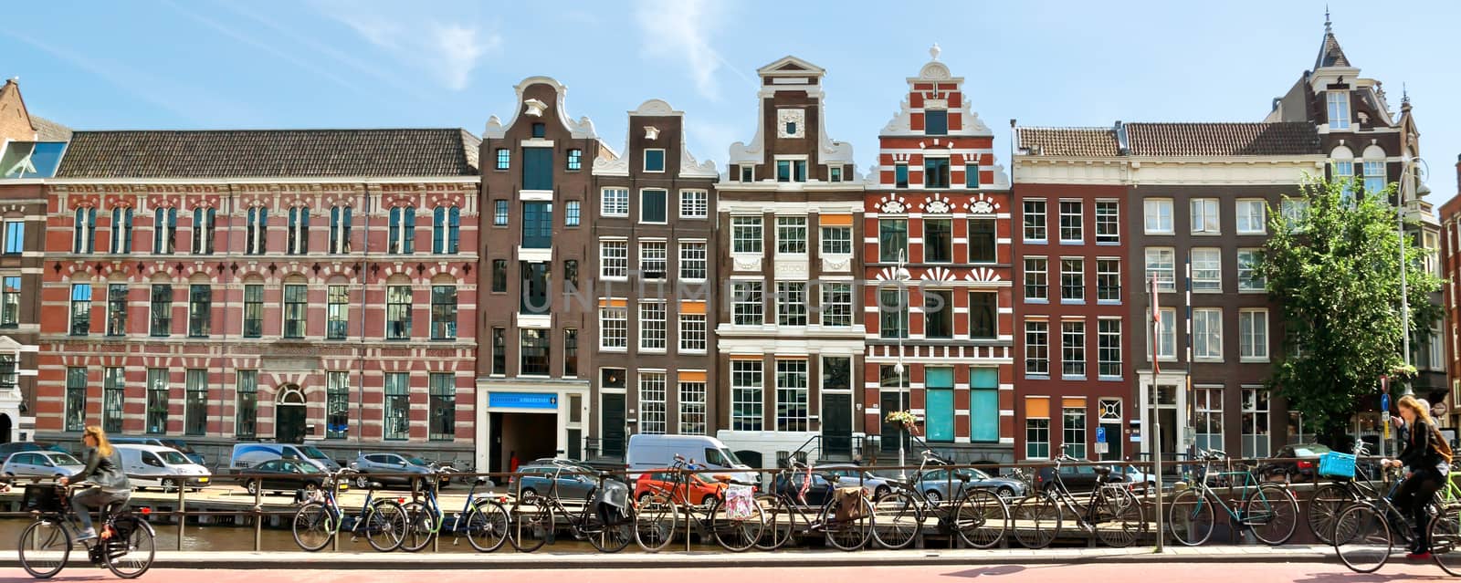 AMSTERDAM, NETHERLANDS - MAY 30: View of Amsterdam city and typical dutch houses on May 30, 2014 in Amsterdam, Netherlands.

Amsterdam, Netherlands - May 30, 2014: View of Amsterdam city and typical dutch houses. People ride bicycles.