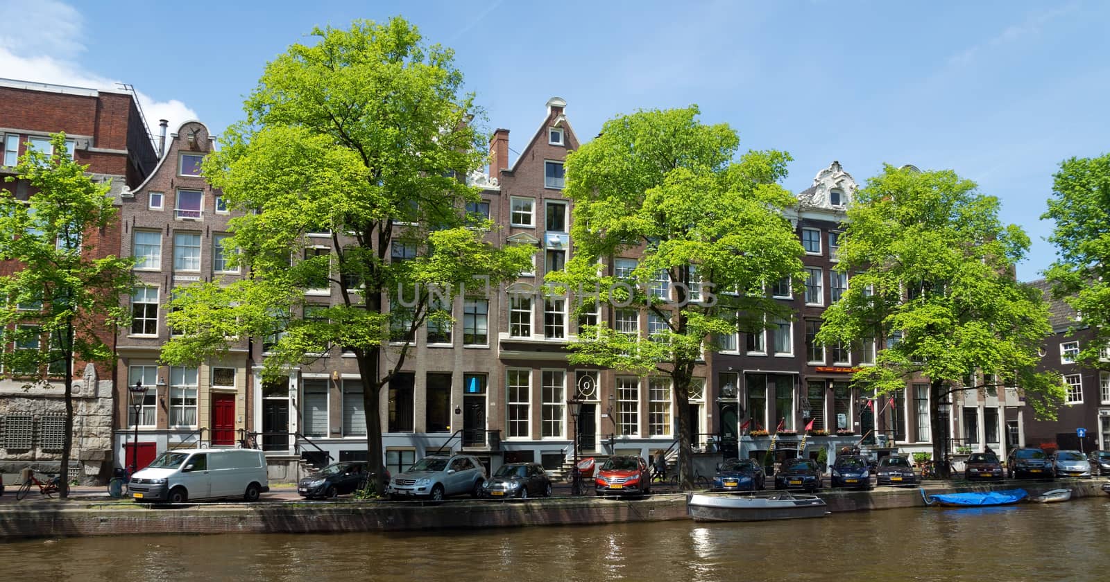 AMSTERDAM, NETHERLANDS - MAY 30: Amsterdam canals on May 30, 2014 in Amsterdam, Netherlands. View of Amsterdam canals and typical dutch houses.

Amsterdam, Netherlands - May 30, 2014: View of Amsterdam canals and typical dutch houses. People are walking by street.