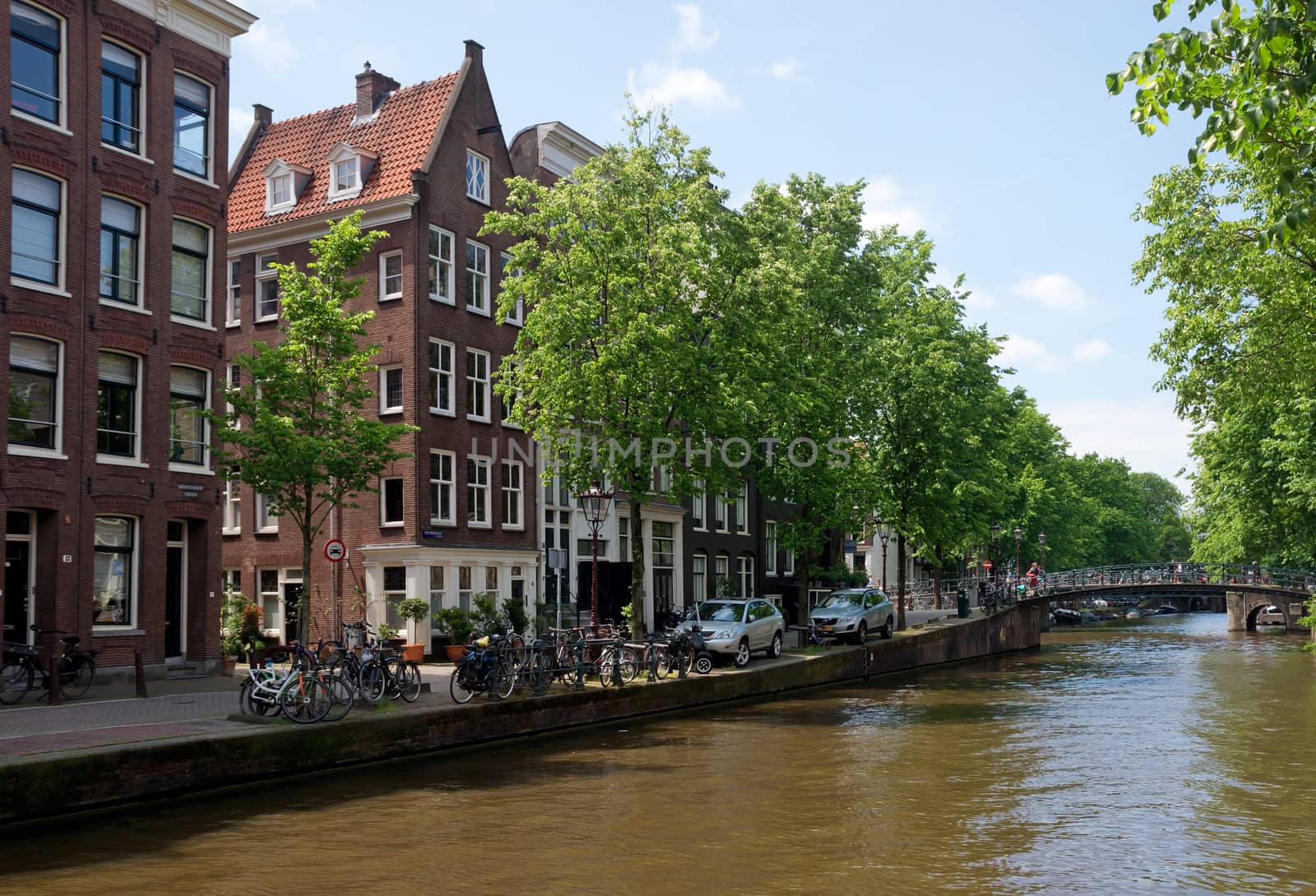 AMSTERDAM, NETHERLANDS - MAY 30: Amsterdam canals on May 30, 2014 in Amsterdam, Netherlands. View of Amsterdam canals and typical dutch houses.

Amsterdam, Netherlands - May 30, 2014: View of Amsterdam canals and typical dutch houses. People are walking by street.