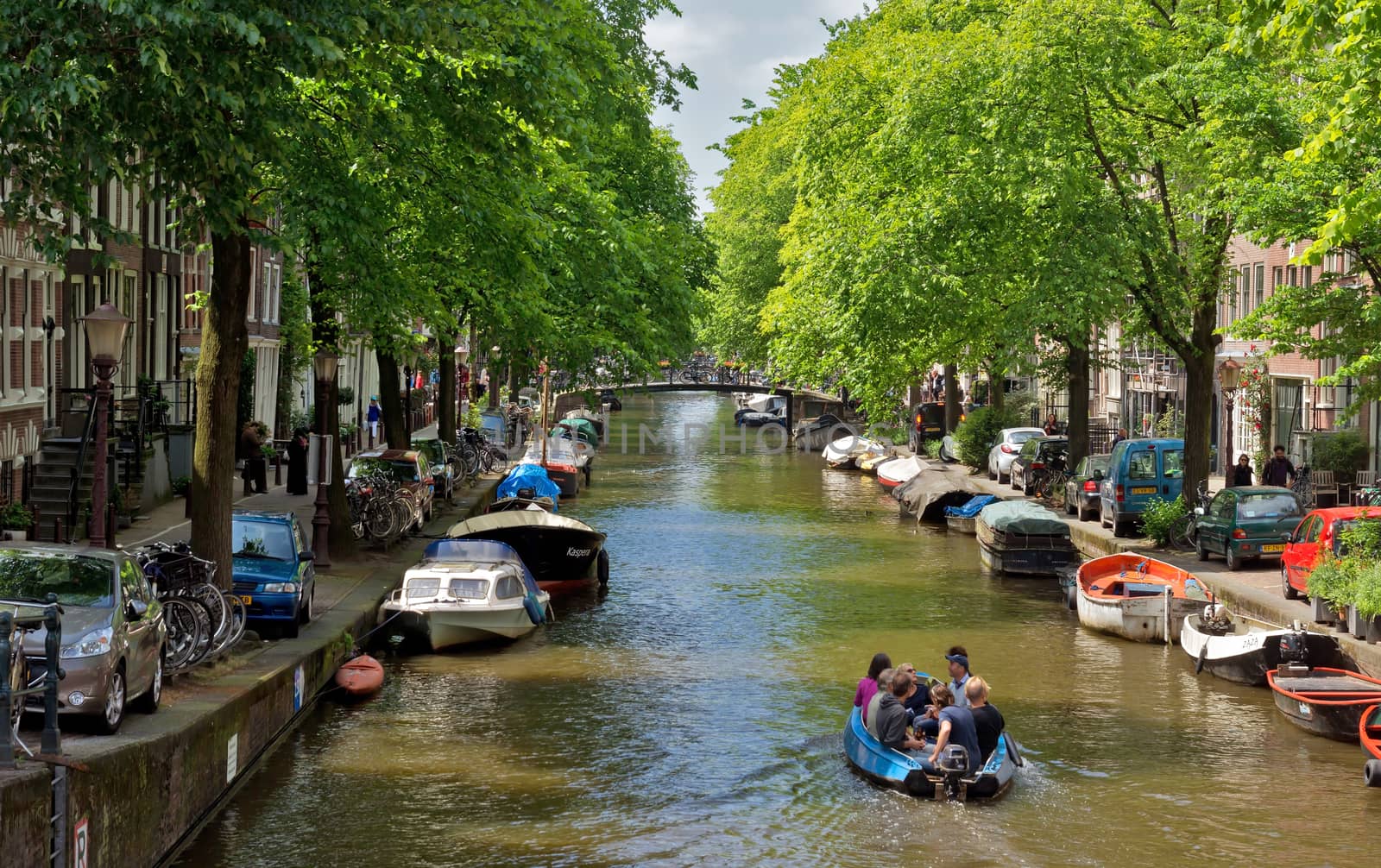 AMSTERDAM, NETHERLANDS - MAY 30: Amsterdam canals on May 30, 2014 in Amsterdam, Netherlands. View of Amsterdam canals and typical dutch houses.

Amsterdam, Netherlands - May 30, 2014: View of Amsterdam canals and typical dutch houses. People are travelling on the boat.