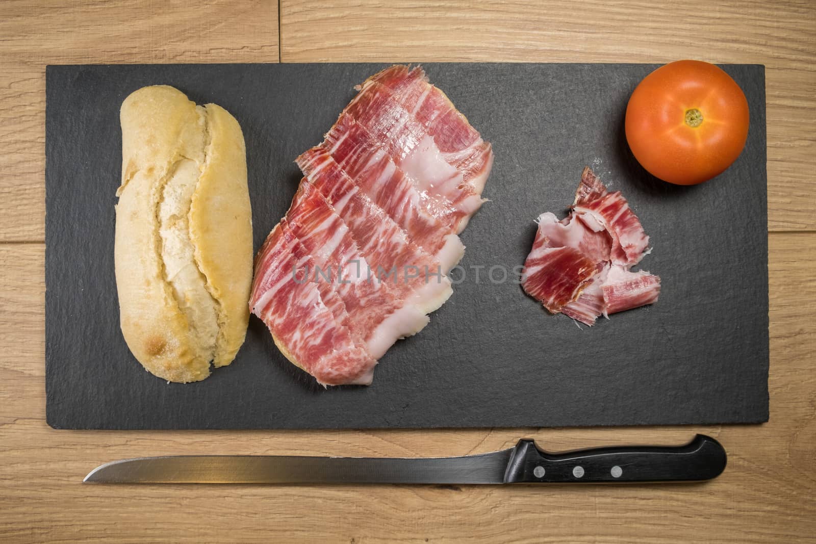 Iberian acorn ham sandwich with its knife, tomato and garlic. Spanish typical tapas