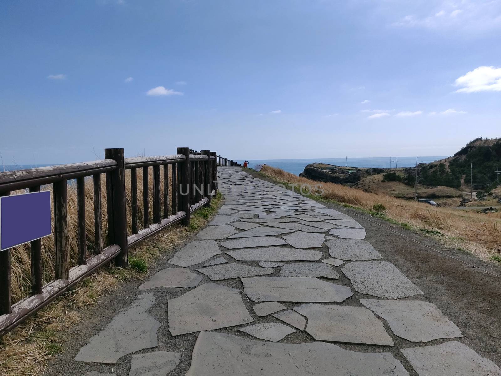 A paved foot path for hikers and walkers in songaksan mountain on the shores of ocean in Jeju Island, South Korea