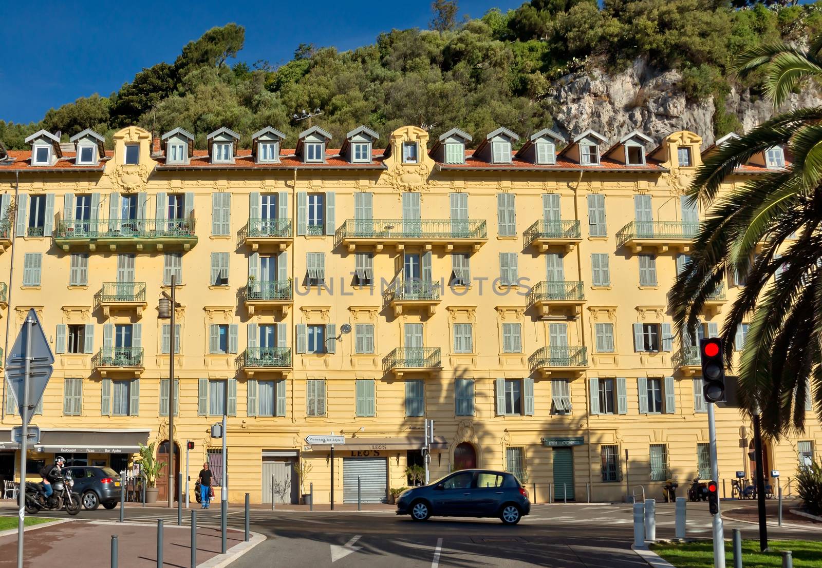 NICE, FRANCE - JUNE 5, 2014: Architecture along Promenade des Anglais. Promenade des Anglais is a symbol of the Cote d'Azur and was built in 1830 at the expense of the British colony.

Nice, France - June 5, 2014: Architecture along Promenade des Anglais. Promenade des Anglais is a symbol of the Cote d'Azur and was built in 1830 at the expense of the British colony. People are walking by street.