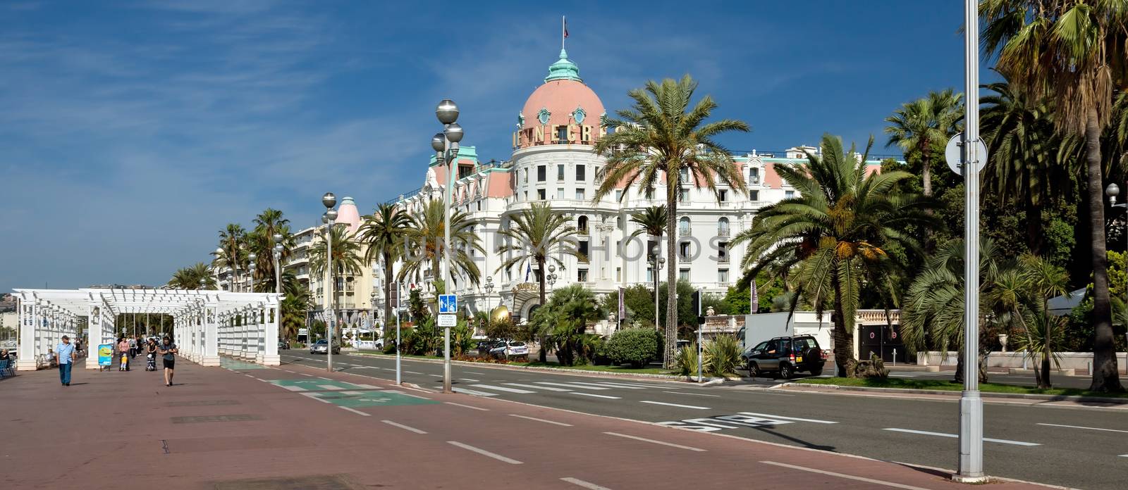 NICE, FRANCE - JUNE 6, 2014: Luxury Hotel Negresco on English Promenade in Nice, French Riviera. Hotel Negresco is the famous luxury hotel on the Promenade des Anglais in Nice, a symbol of the Cote d'Azur.

Nice, France - June 6, 2014: Luxury Hotel Negresco on English Promenade in Nice, French Riviera. Hotel Negresco is the famous luxury hotel on the Promenade des Anglais in Nice, a symbol of the Cote d'Azur. People are walking by Promenade.