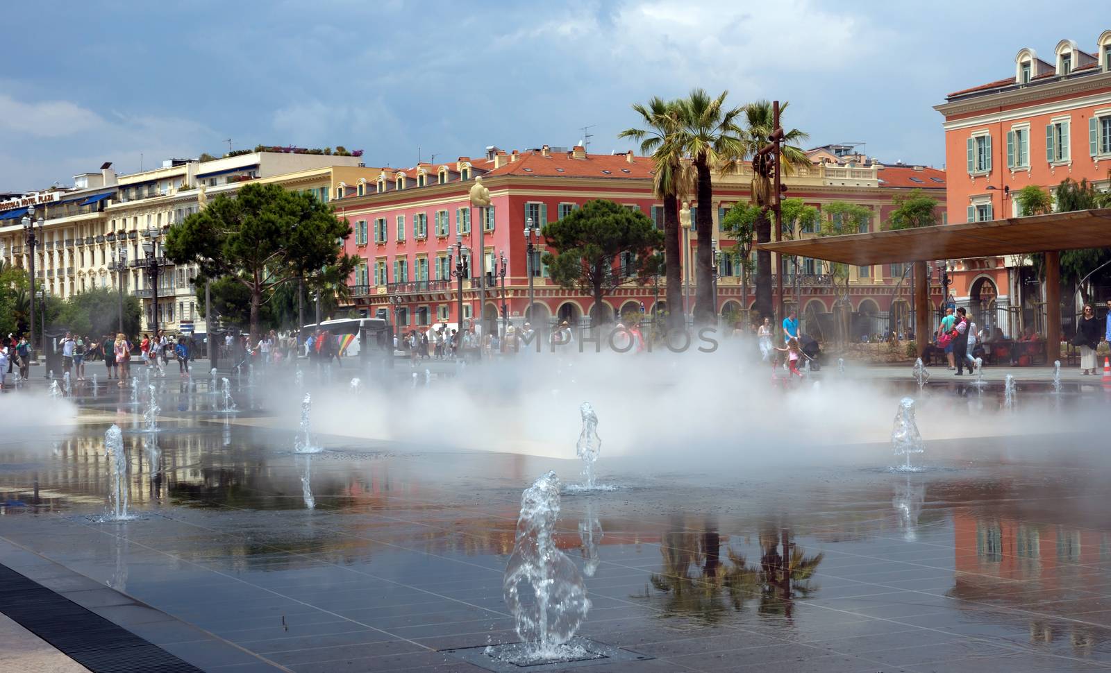 NICE, FRANCE - JUNE 4, 2014: Lovely fountain on Place Massena in Nice. Place Massena is Main Square of the city and it is used for concerts and other events which take place in the city.

Nice, France - June 4, 2014: Lovely fountain on Place Massena in Nice. Place Massena is Main Square of the city and it is used for concerts and other events which take place in the city. People are walking near fountain.