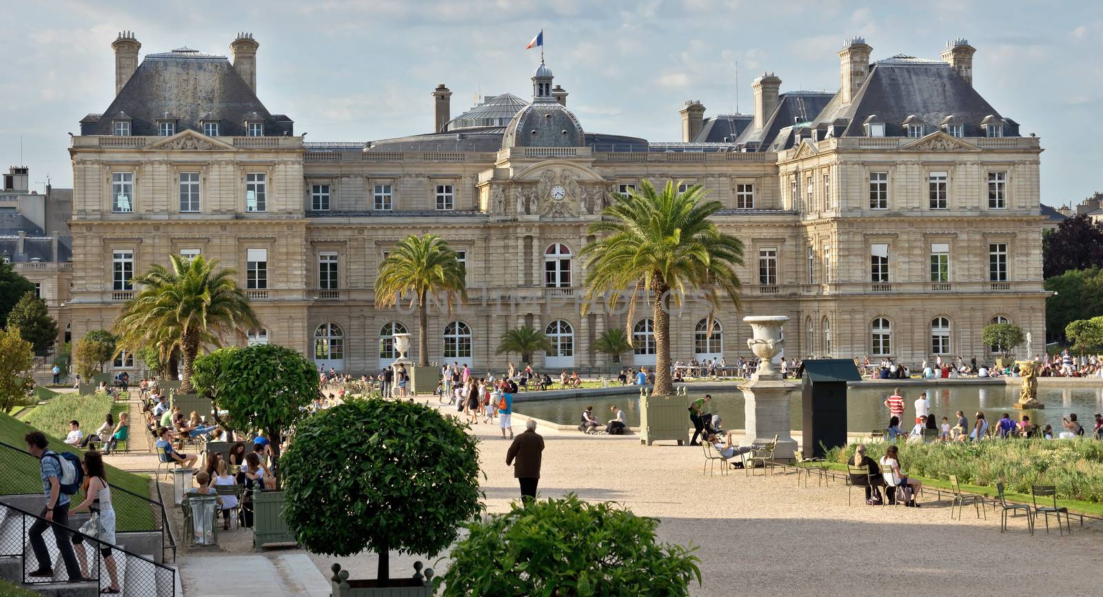 PARIS, FRANCE - JUNE 8, 2014: The Luxembourg Palace in The Jardin du Luxembourg. View on the main facade and water pond.

Paris, France - June 8, 2014: The Luxembourg Palace in The Jardin du Luxembourg. View on the main facade and water pond. Many people are resting there.
