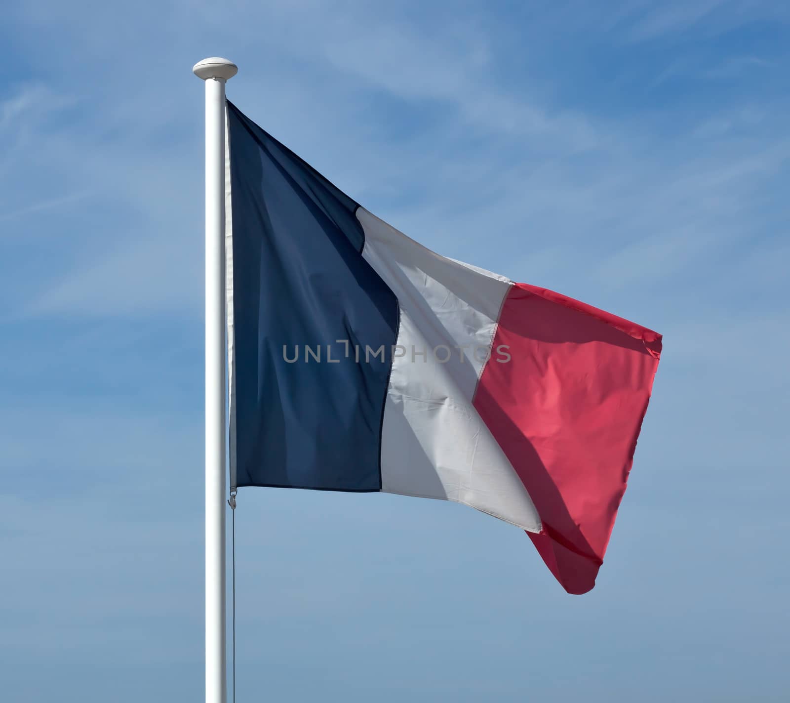 Flag of France waving against blue sky.