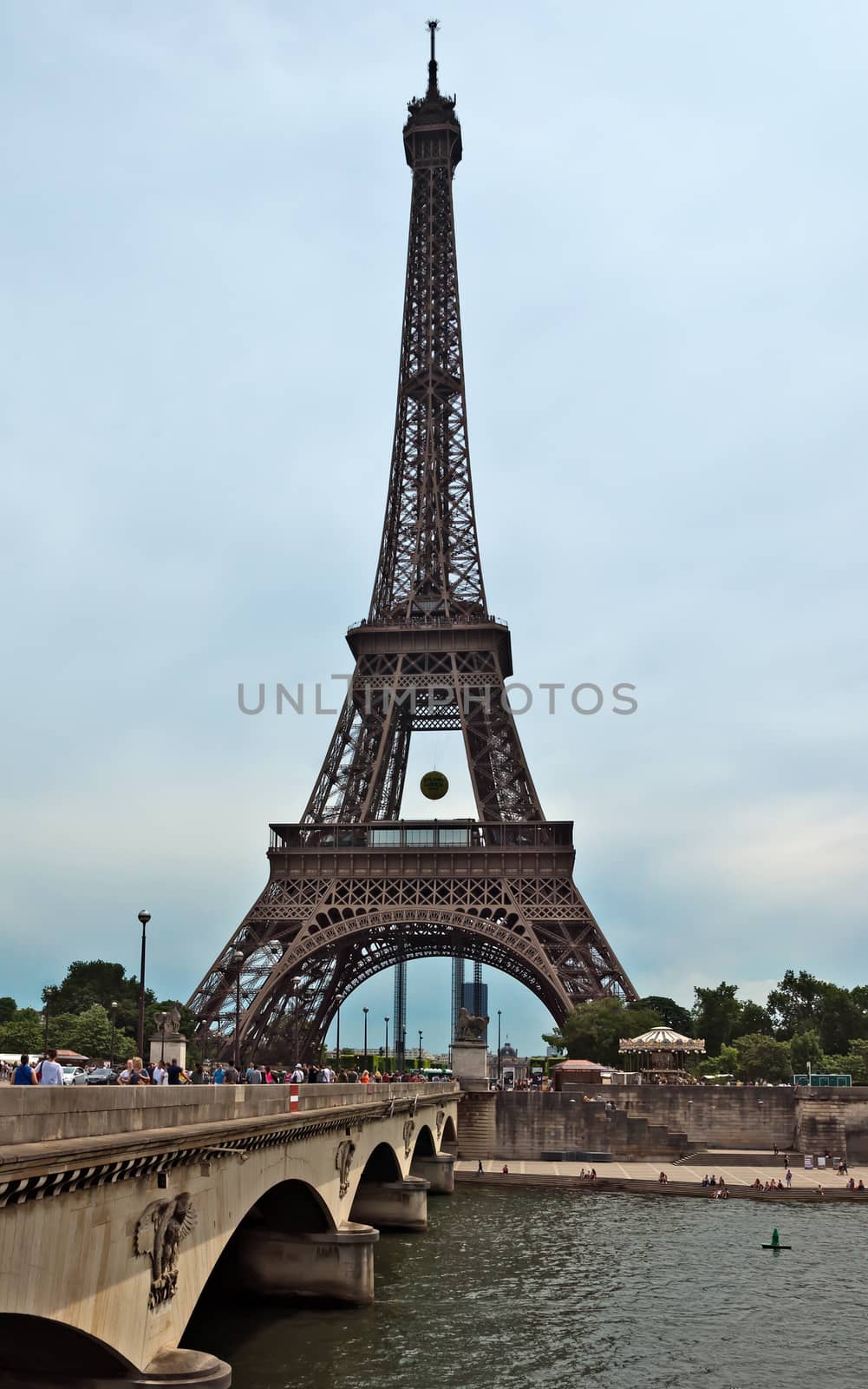 PARIS, FRANCE - JUNE 9, 2014: Eiffel tower and old bridge over Seine river. The Eiffel tower is the most visited monument of Paris.

Paris, France - June 9, 2014: Eiffel tower and old bridge over Seine river. The Eiffel tower is the most visited monument of Paris. People are walking across the bridge.