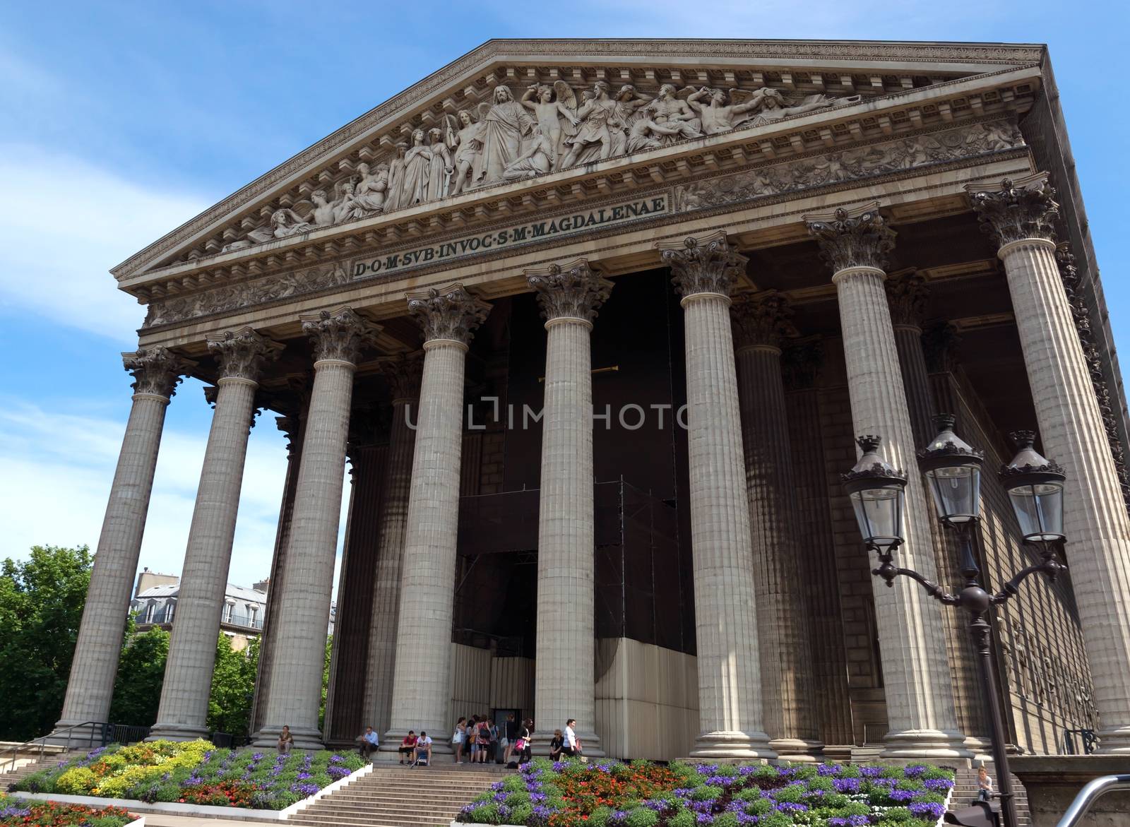 PARIS, FRANCE - JUNE 11: Eglise de la Madeleine Church on June 11, 2014 in Paris, France. Madeleine Church was designed in its present form as a temple to the glory of Napoleon's army.

Paris, France - June 11, 2014: Eglise de la Madeleine Church. Madeleine Church was designed in its present form as a temple to the glory of Napoleon's army. People sit and stand near the church.