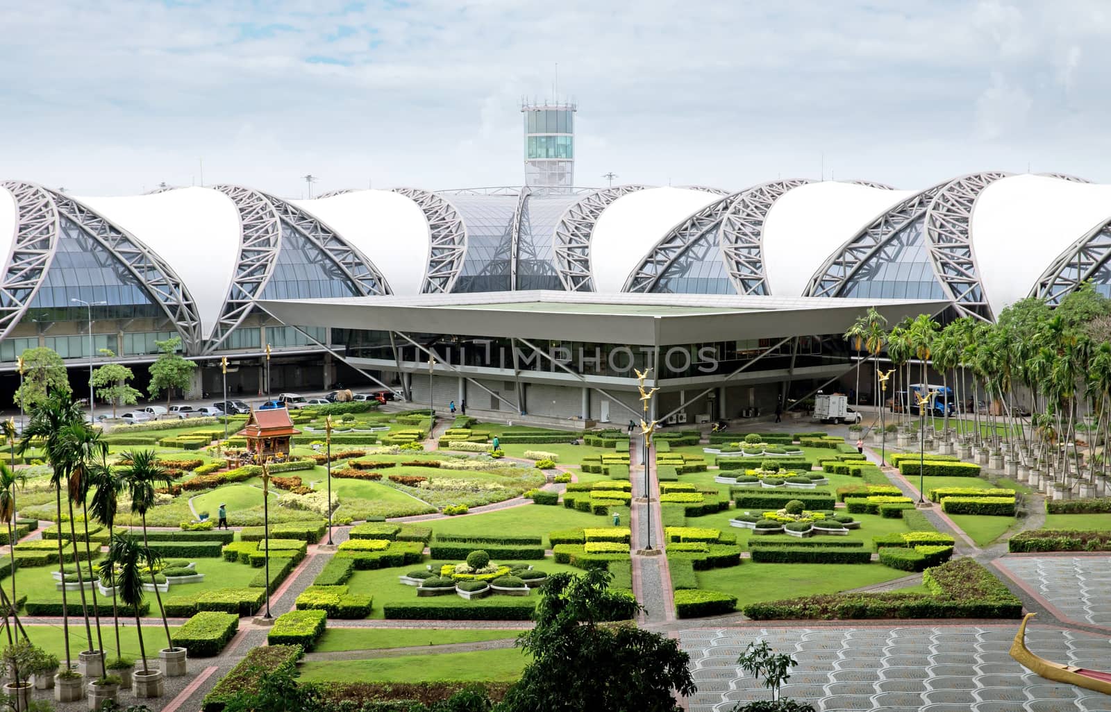 BANGKOK, THAILAND - JULY 21: Suvarnabhumi Airport is the world's third largest single-building airport terminal on July 21, 2013 in Bangkok, Thailand. Designed by Helmut Jahn.

Bangkok, Thailand - July 21, 2013: Suvarnabhumi Airport is the world's third largest single-building airport terminal. Designed by Helmut Jahn. People are walking in the park.