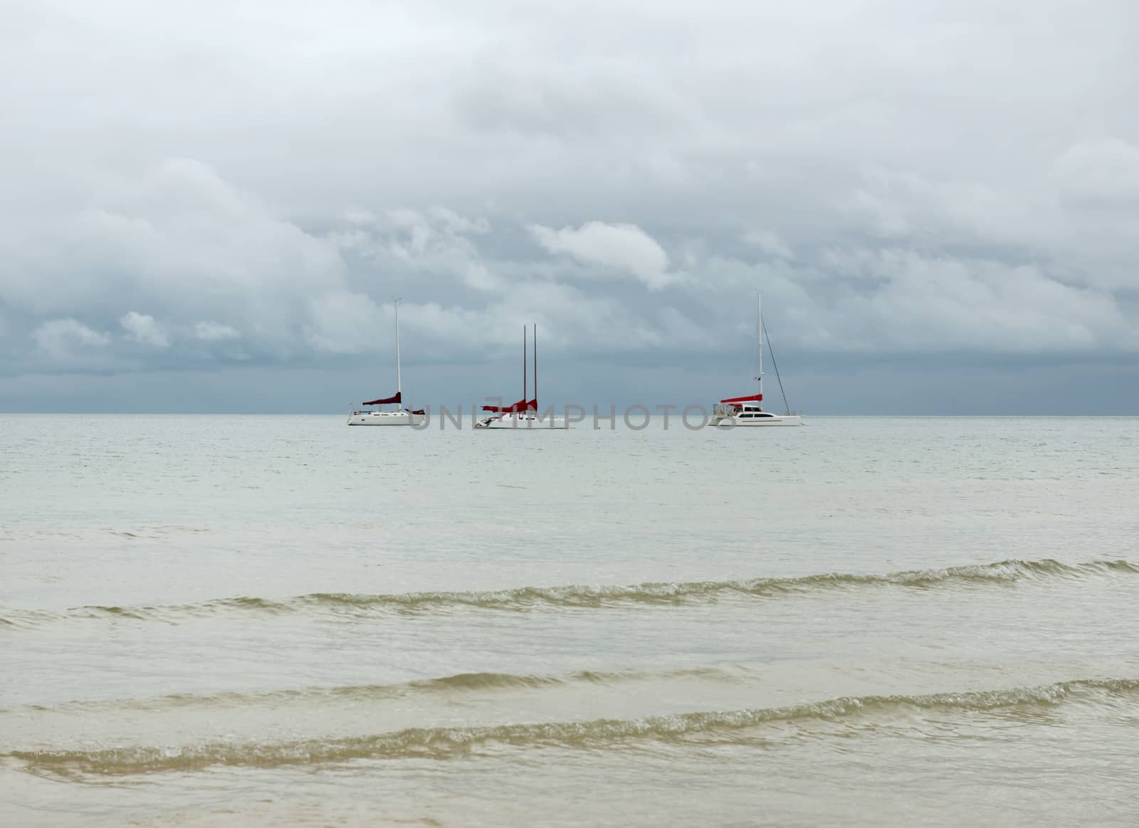 Tropical sea with three lonely yachts on the horizon