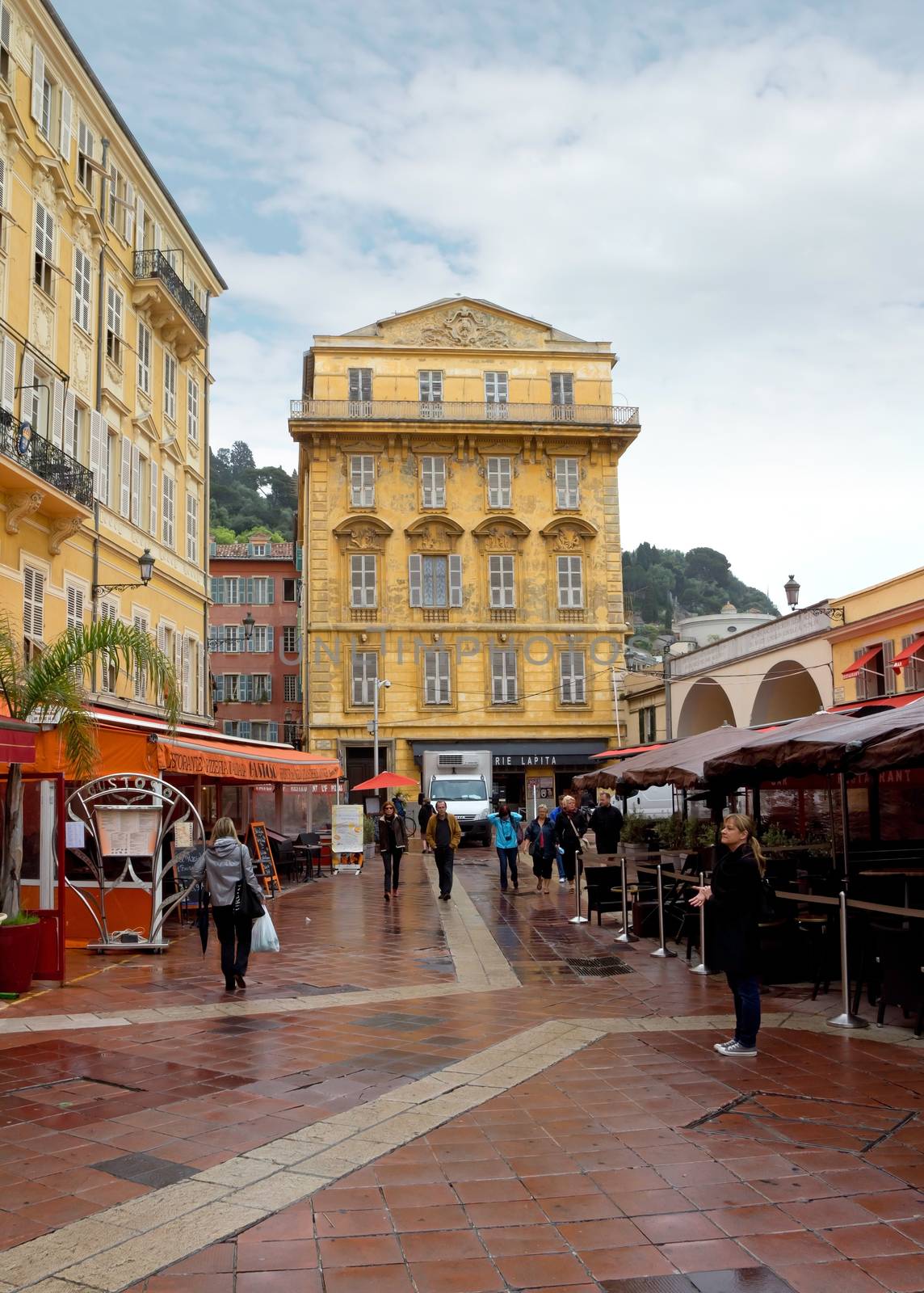NICE, FRANCE - APRIL 27: Old building and a cafe in the Cours Saleya on April 27, 2013 in Nice, France. The Cours Saleya is a place of outdoor restaurants and a market. 

Nice, France - April 27, 2013: Old building and a cafe in the Cours Saleya. People are walking and relaxing.
The Cours Saleya is a place of outdoor restaurants, boutiques and a market. 