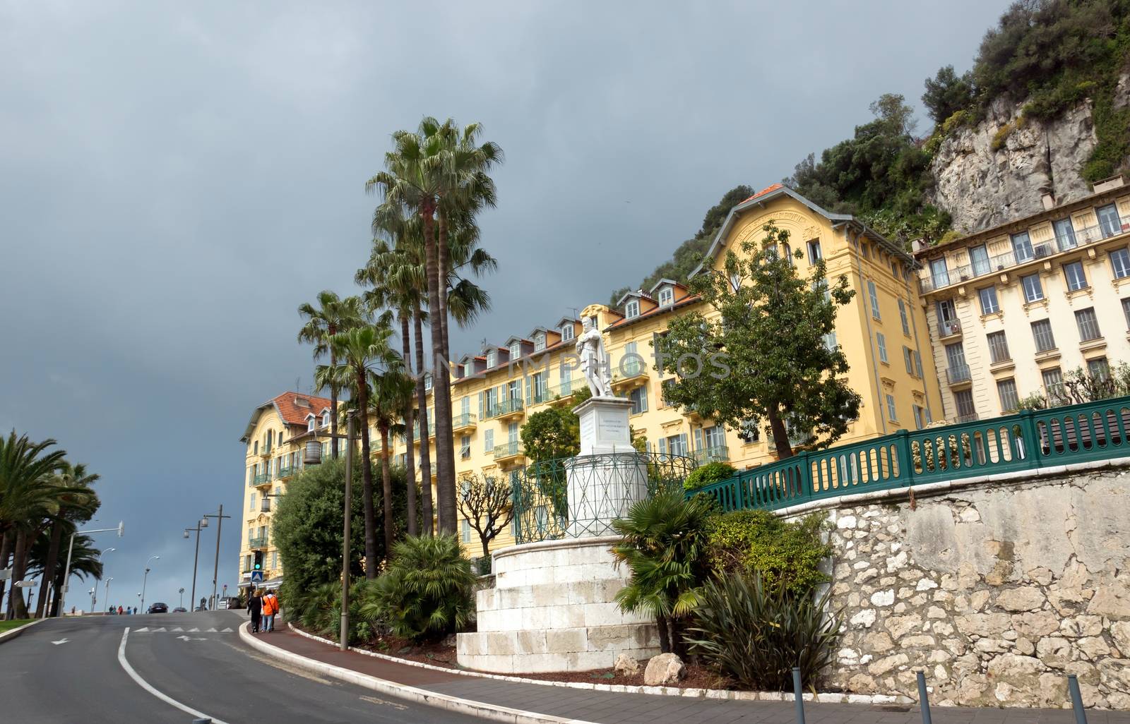 NICE, FRANCE - APRIL 27: Architecture along Promenade des Anglais on April 27, 2013 in Nice, France. It is a symbol of the Cote d'Azur and was built in 1830 at the expense of the British colony.

Nice, France - April 27, 2013: Architecture along Promenade des Anglais. People are walking. Promenade des Anglais is a symbol of the Cote d'Azur and was built in 1830 at the expense of the British colony.