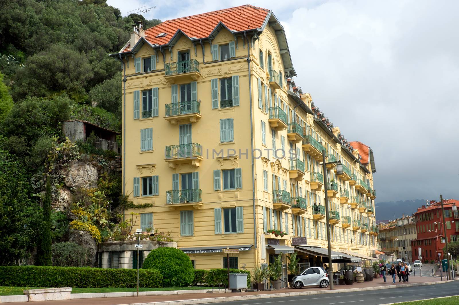NICE, FRANCE - APRIL 27: Architecture along Promenade des Anglais on April 27, 2013 in Nice, France. It is a symbol of the Cote d'Azur and was built in 1830 at the expense of the British colony.

Nice, France - April 27, 2013: Architecture along Promenade des Anglais. People are walking. Promenade des Anglais is a symbol of the Cote d'Azur and was built in 1830 at the expense of the British colony.