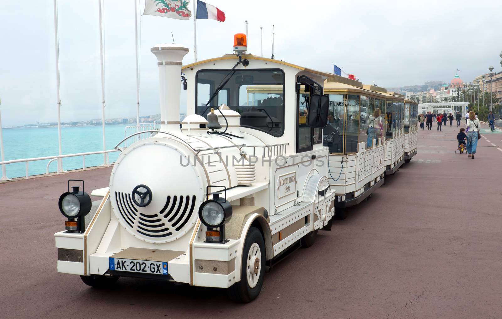 NICE, FRANCE - APRIL 27: White trackless train for sightseeing on the Promenade des Anglais on April 27, 2013 in Nice, France. People are walking along Promenade des Anglais.

Nice, France - April 27, 2013 : White trackless train for sightseeing on the Promenade des Anglais in Nice. People are walking along Promenade des Anglais.