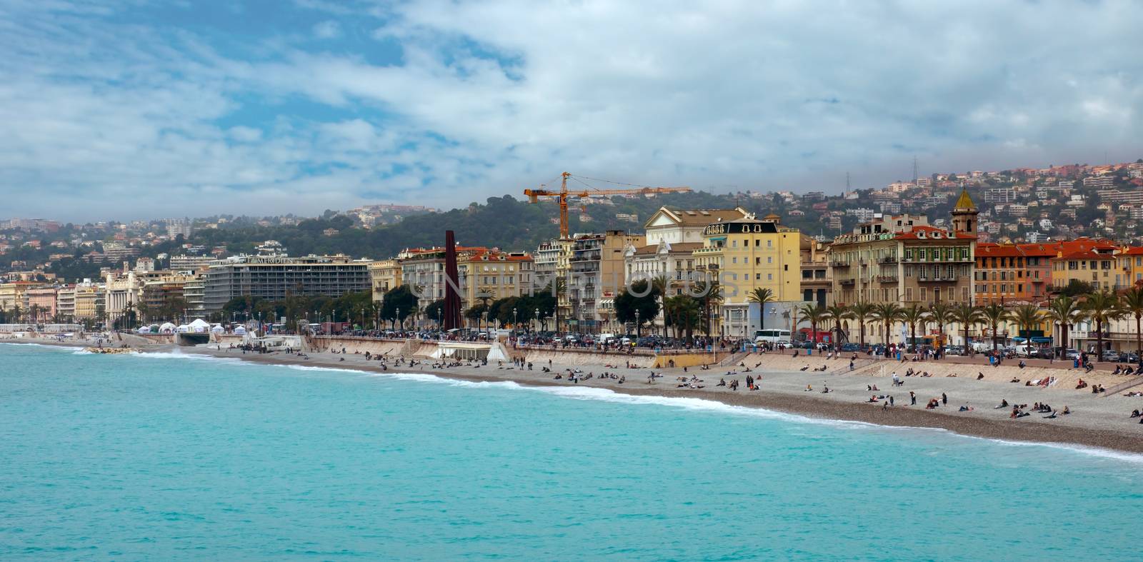 NICE, FRANCE - APRIL 27: Architecture along Promenade des Anglais on April 27, 2013 in Nice, France. It is a symbol of the Cote d'Azur and was built in 1830 at the expense of the British colony.

Nice, France - April 27, 2013: Architecture along Promenade des Anglais. People are resting. Promenade des Anglais is a symbol of the Cote d'Azur and was built in 1830 at the expense of the British colony.