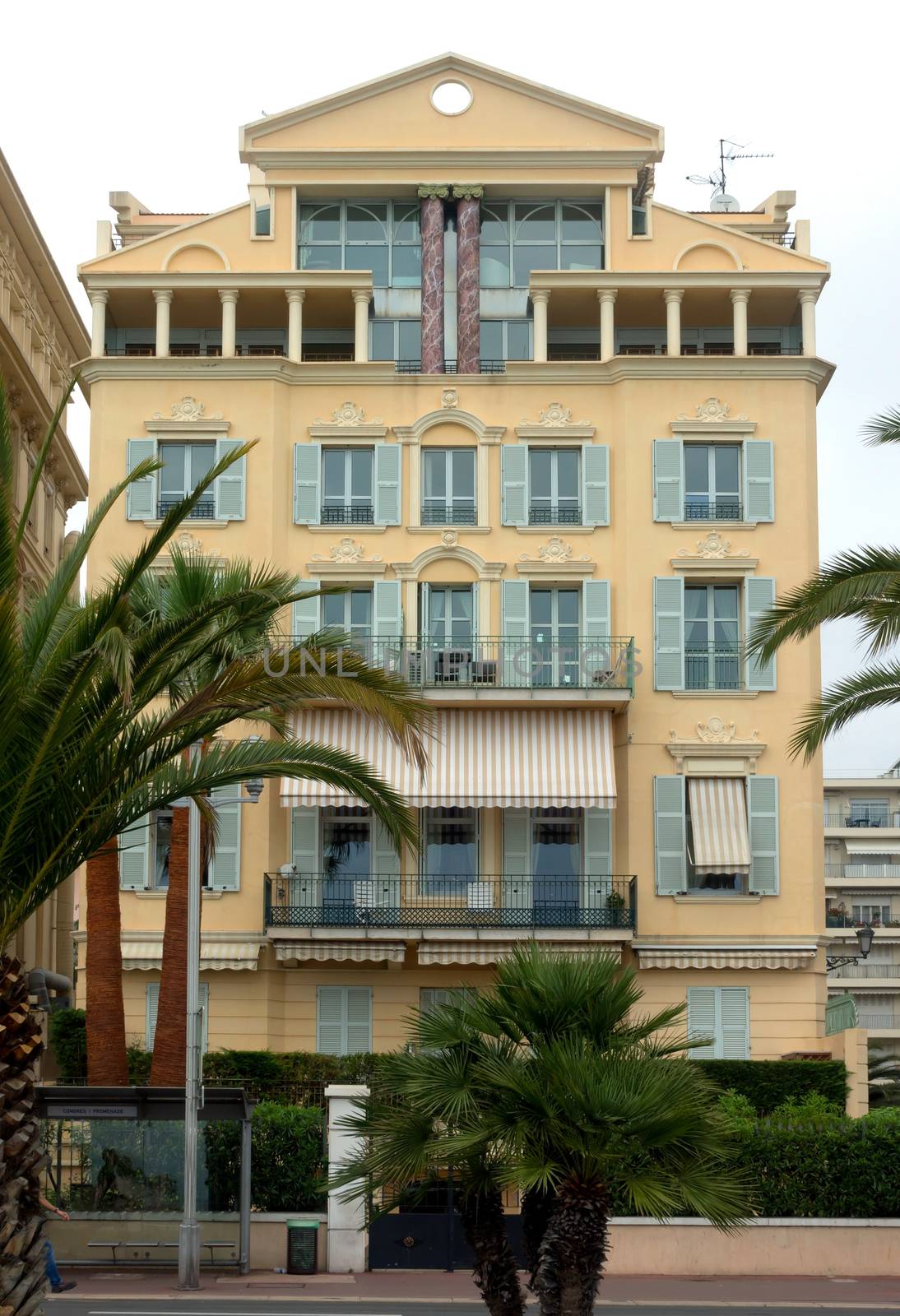 NICE, FRANCE - APRIL 27: Architecture along Promenade des Anglais on April 27, 2013 in Nice, France. It is a symbol of the Cote d'Azur and was built in 1830 at the expense of the British colony.

Nice, France - April 27, 2013: Architecture along Promenade des Anglais. Promenade des Anglais is a symbol of the Cote d'Azur and was built in 1830 at the expense of the British colony. People are resting in cafe.