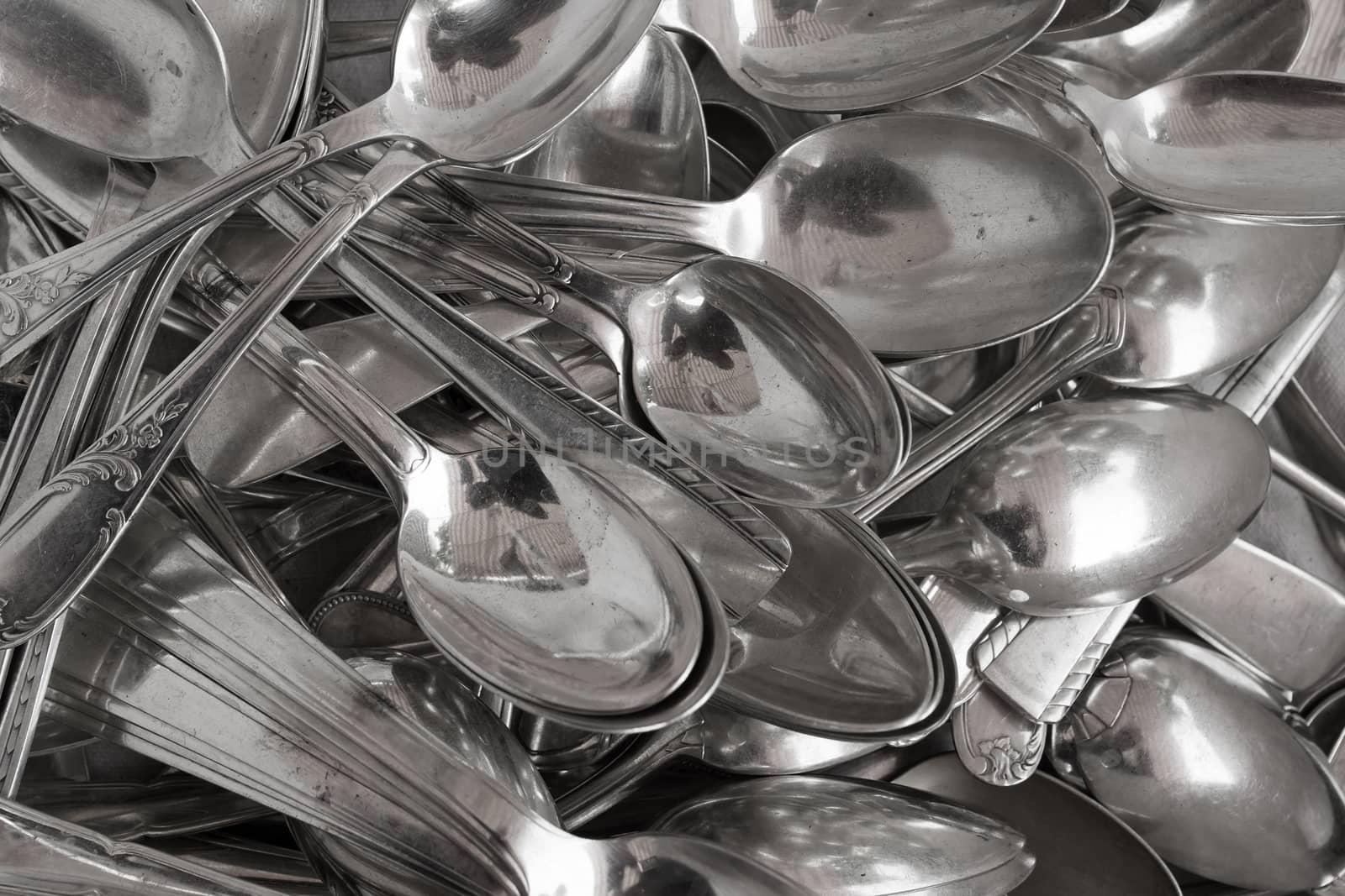 Background of heap old fashioned silver spoons.
