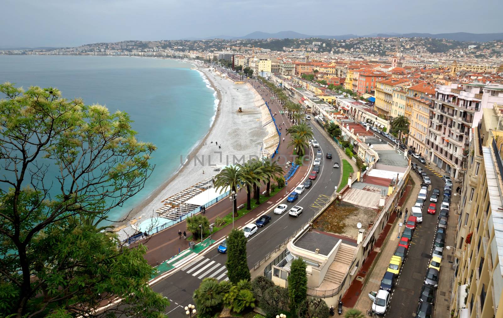 NICE, FRANCE - APRIL 29: Architecture along Promenade des Anglais on April 29, 2013 in Nice, France. It is a symbol of the Cote d'Azur and was built in 1830 at the expense of the British colony.

Nice, France - April 29, 2013: Architecture along Promenade des Anglais. People are resting. Promenade des Anglais is a symbol of the Cote d'Azur and was built in 1830 at the expense of the British colony.