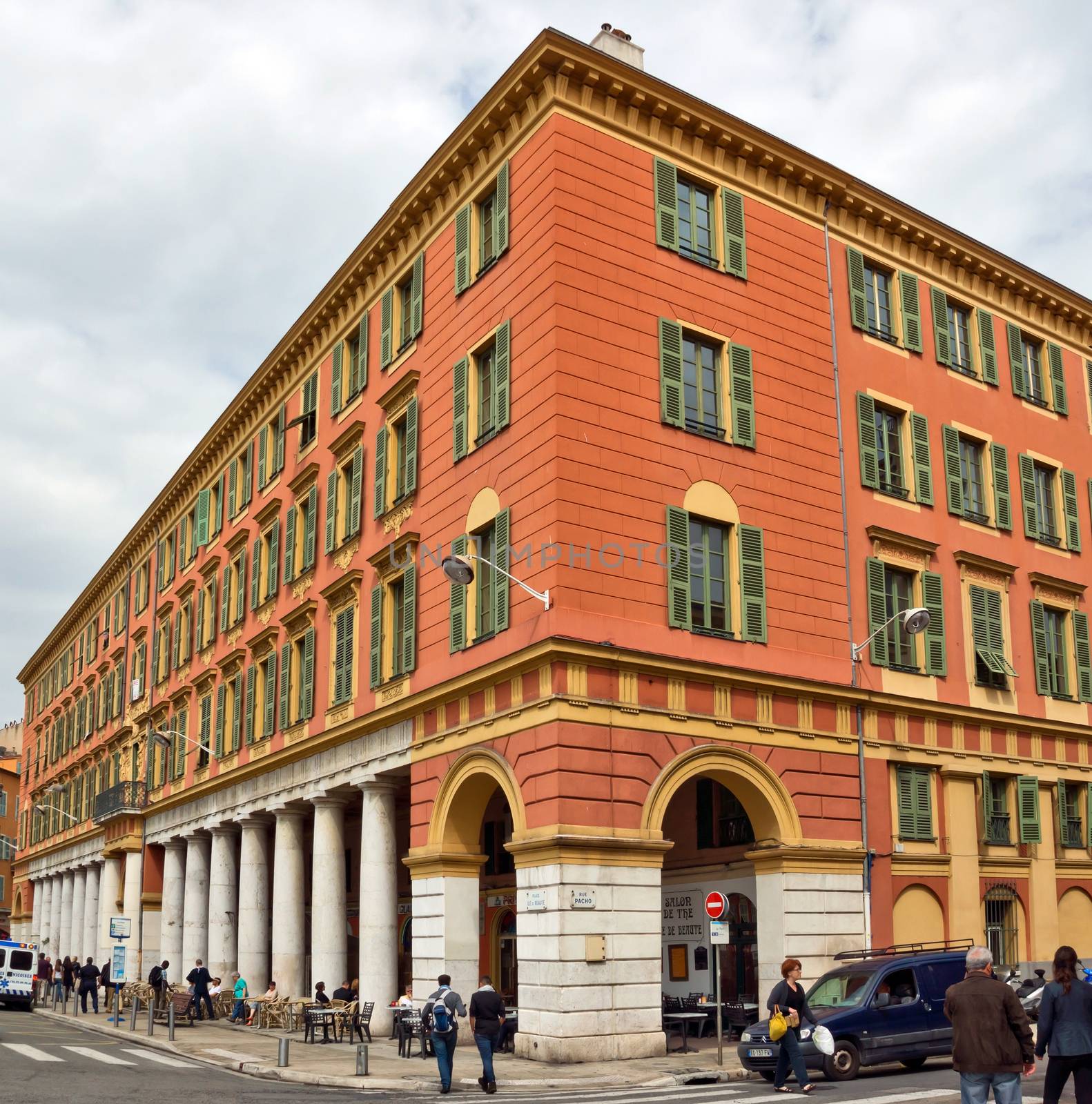 NICE, FRANCE - APRIL 30: The architecture of buildings on the Place Massena on April 30, 2013 in Nice, France. The square is bordered by red ochre buildings of Italian architecture.

Nice, France - April 30, 2013: The architecture of buildings on the Place Massena. The square is bordered by red ochre buildings of Italian architecture. People are walking by street.