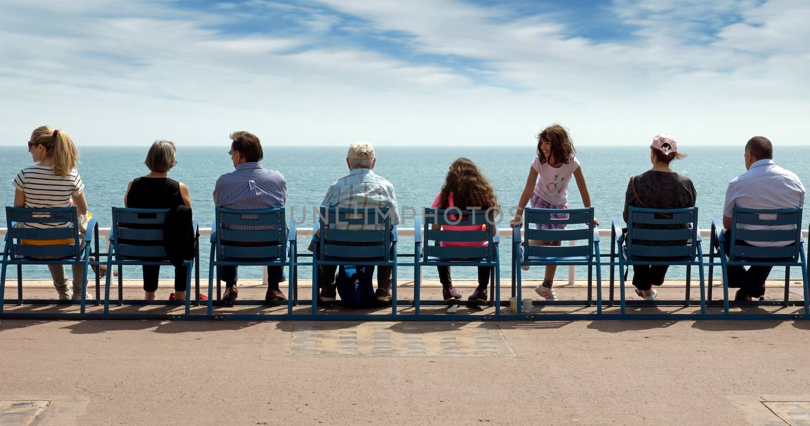NICE, FRANCE - MAY 2: People sit on chairs along Promenade des Anglais and enjoy the view of the Mediterranean Sea on May 2, 2013 in Nice, France. Nice is a popular Mediterranean tourist destination, attracting 4 million visitors each year. 

Nice, France - May 2, 2013: People sit on chairs along Promenade des Anglais and enjoy the view of the Mediterranean Sea. Nice is a popular Mediterranean tourist destination, attracting 4 million visitors each year.